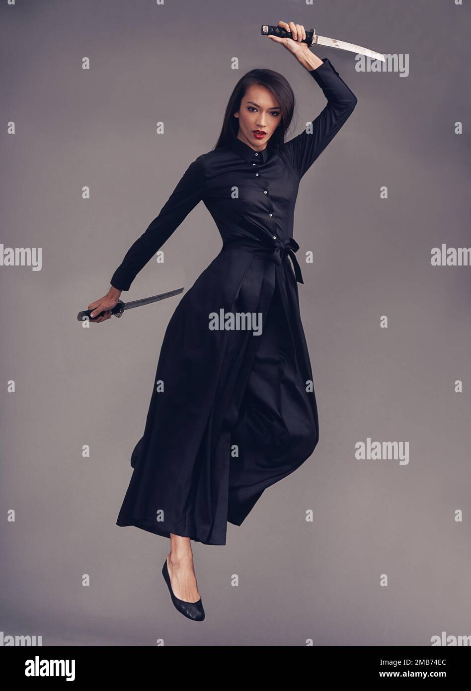 Ninja, Klinge und weibliche Kriegerin in einem Studio, die für Kampfkunst oder Kampfkunst-Kampfkunst-Fähigkeiten springen. Fantasie, Cosplay und Porträt eines weiblichen Modells in einem Stockfoto