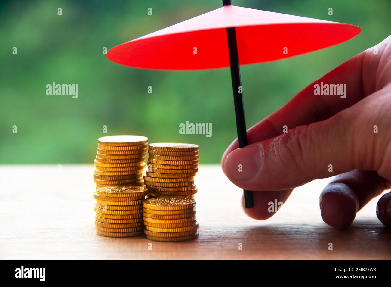 Schirm über Goldmünze mit verschwommenem Naturhintergrund. Sicherheit, finanzielle Unabhängigkeit, Sicherheit und Sicherheitskonzept Stockfoto