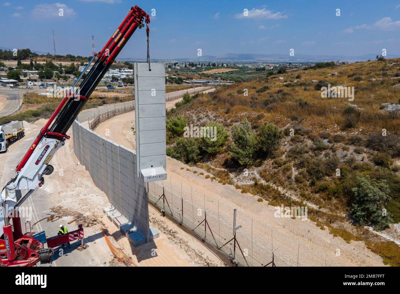Workers place a nine-meter (30-foot) high concrete wall that replaces a border fence between the northern West Bank and Israel near the Arab village of Salem, Wednesday, June 22, 2022. The Israeli defense ministry said Wednesday that it had started construction on a section of separation barrier in the northern West Bank after months of military raids in the area following a string of deadly attacks on Israelis by Palestinians. The ministry announced that its department of engineering and the military began work on a 45-kilometer (28 mile) stretch of wall to replace fencing installed 20 years Stockfoto