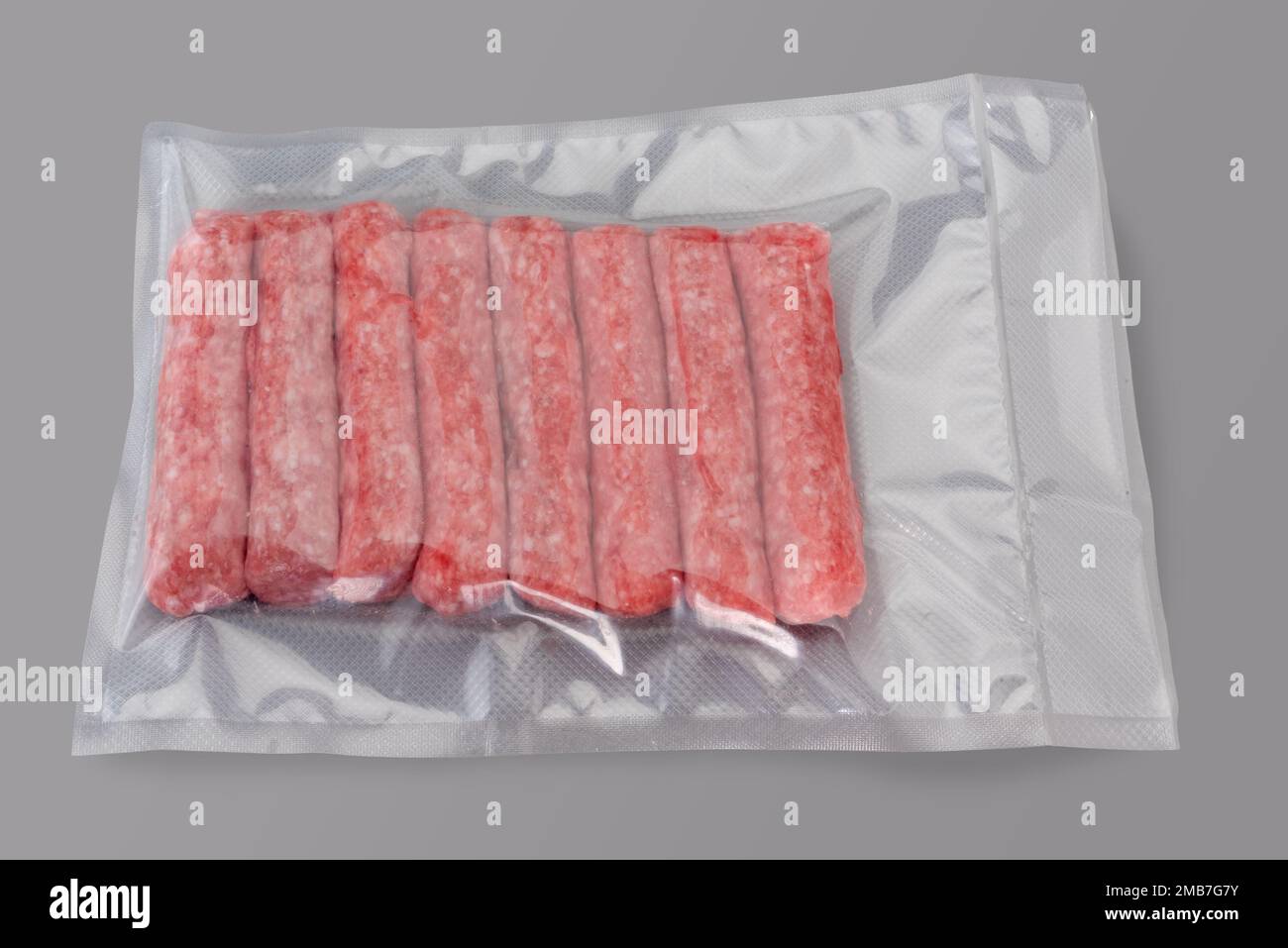 Rohe truthahn- und Schweinefleischwurst in vakuumverpackter Verpackung, versiegelt für Sous-Vide-Kochen, isoliert auf grauem Hintergrund in Draufsicht Stockfoto