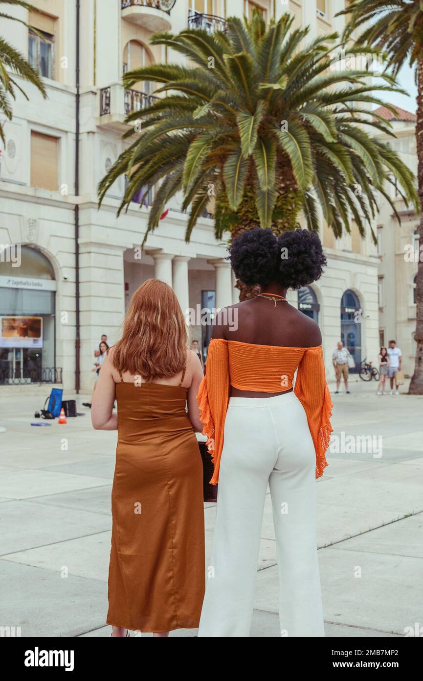 Junge, stilvolle Frauen in Sommerbekleidung, die auf dem Marktplatz posieren Stockfoto