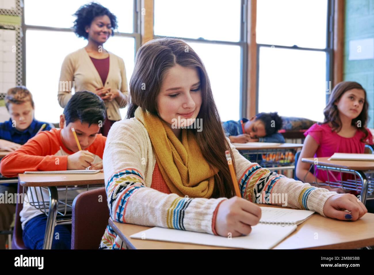 Ausbildung, Schreiben und Prüfung mit Kindern im Klassenzimmer der Hochschule für Akademie, Wissen und Lernen. Studium, Schule und Notizbuch mit Schülern und Stockfoto