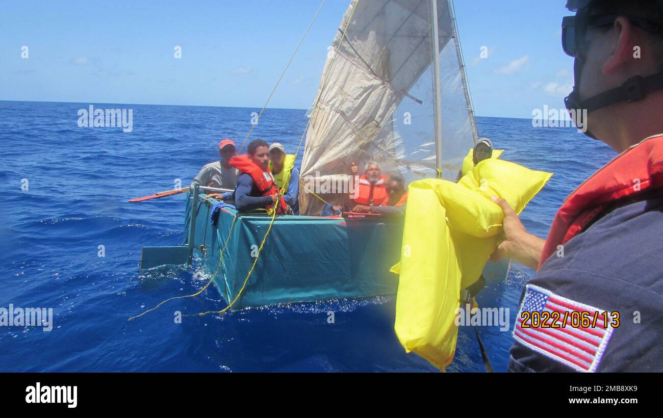 Ein Crewmitglied von Coast Guard Cutter Issac Mayo überreicht Rettungswesten an Leute an Bord eines rustikalen, unsicheren Schiffes, etwa 17 Meilen südlich von Boca Chica, Florida, am 13. Juni 2022. Die Menschen wurden am 17. Juni 2022 nach Kuba zurückgeführt. Stockfoto