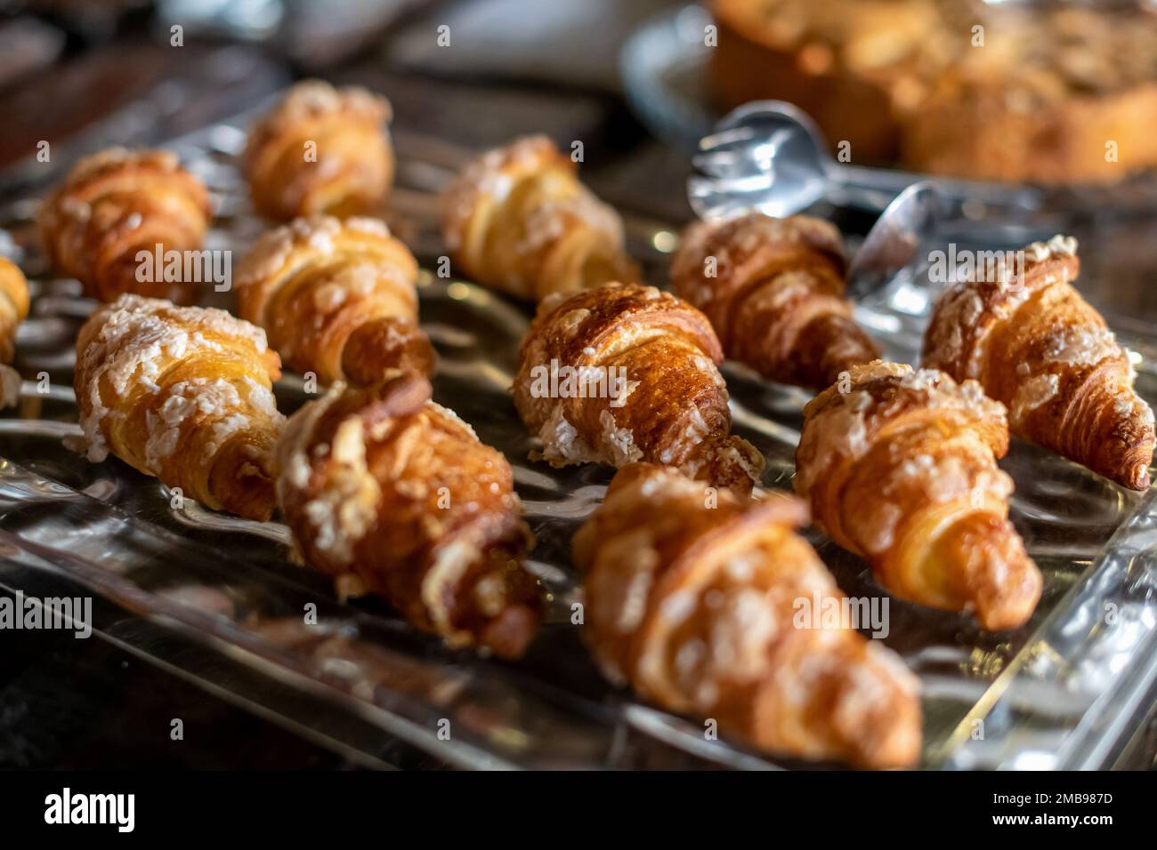 In der Bäckerei werden viele leckere kleine Croissants in einem hohen Winkel auf ein Tablett gestellt Stockfoto