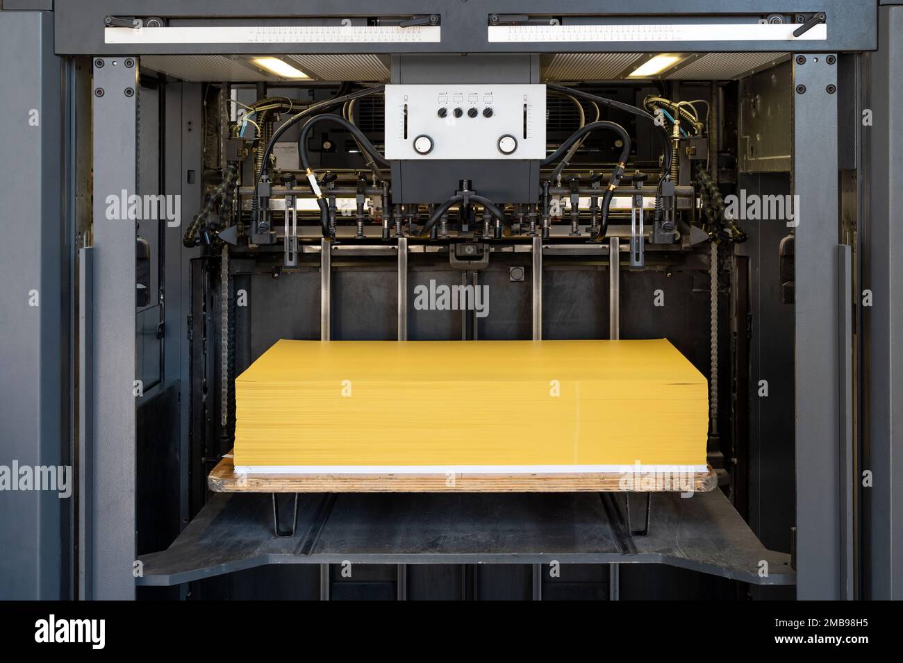 Moderner Industriedrucker mit einem Stapel gelber Blätter in der Fabrik zur Herstellung und Verarbeitung von Papier Stockfoto