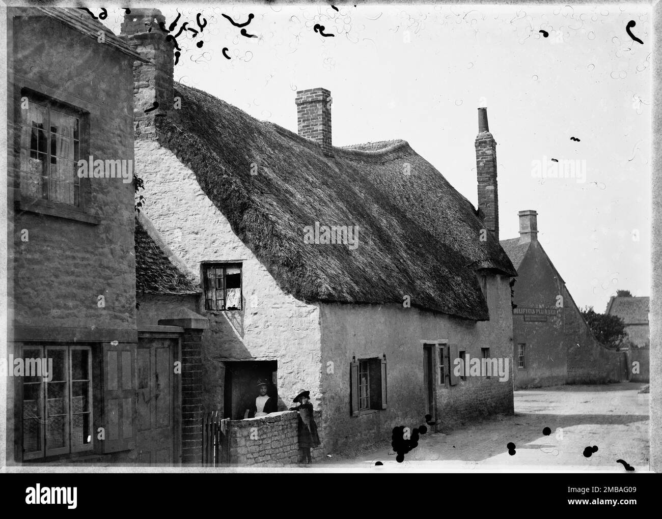 Little Strohgedeckte Hütte, Church Street, Eynsham, West Oxfordshire, 1885. Die Aussicht auf den Südwesten entlang der Church Street zeigt ein kleines strohgedecktes Cottage und ein großes strohgedecktes Cottage. Stockfoto