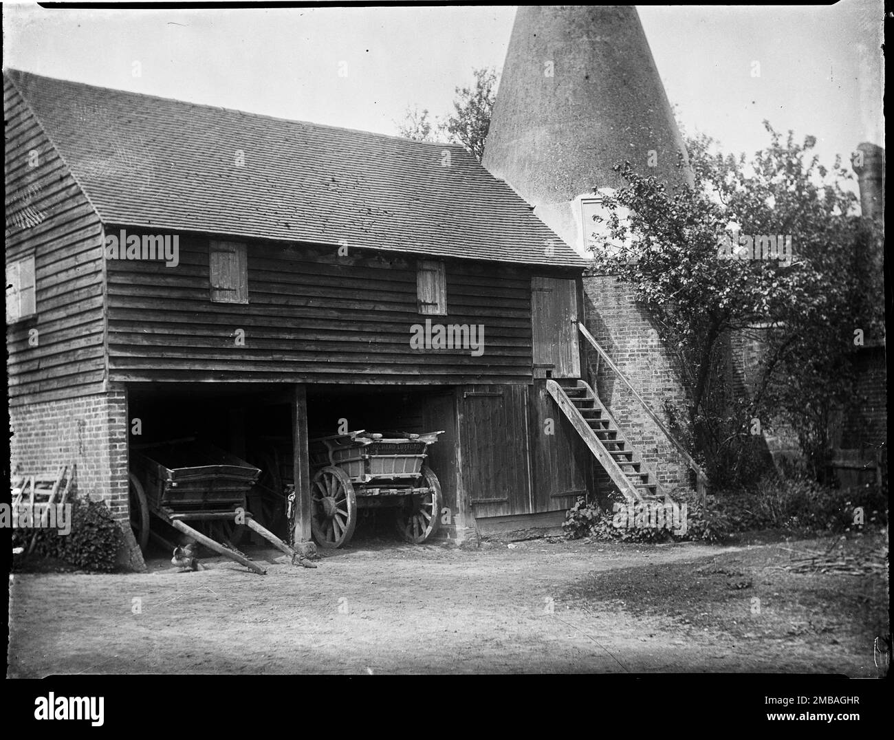 Florence Farm, Groombridge, Withyham, Wealden, East Sussex, 1911. Außenansicht von Südosten des Oasthouse und der Stauscheune auf der Farm Florence, mit zwei Wagen im Schuppen für Karren im Erdgeschoss der Scheune. Stockfoto