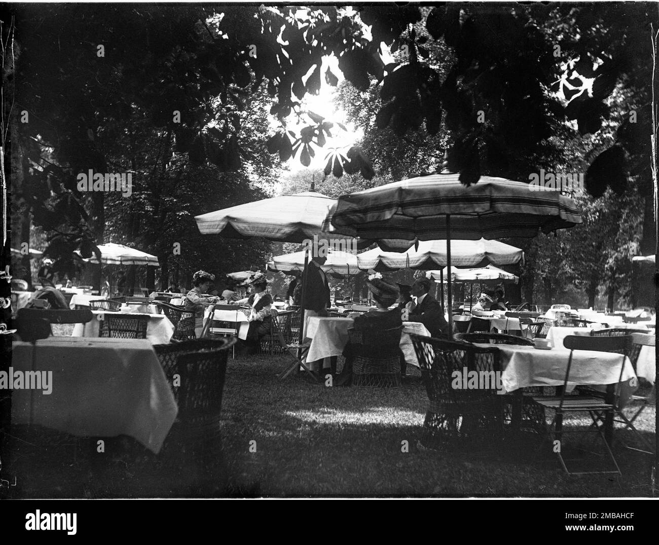 Hyde Park, City of Westminster, Greater London Authority, 1905. Ein Teegarten im Hyde Park, in dem ein Kellner einen Tisch mit Gästen serviert, der unter einem Sonnenschirm sitzt. Stockfoto