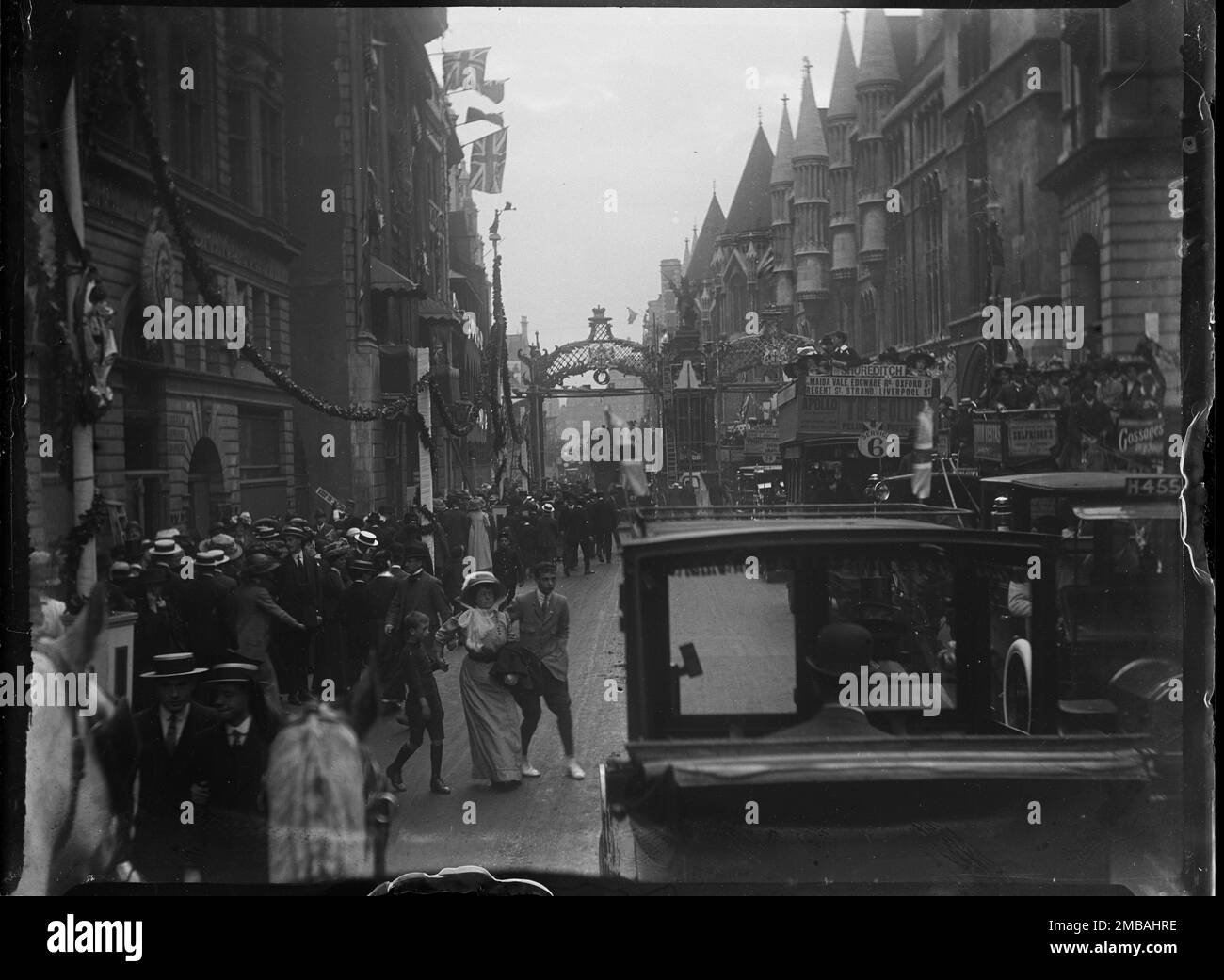 Fleet Street, City of London, Greater London Authority, 1911. Blick nach Westen entlang der Fleet Street in Richtung Temple Bar Memorial, wo Wimpel und Dekorationen für die Krönung von König George V. und Königin Mary erbaut wurden. Im Vordergrund versuchen eine Frau und zwei Jungen, die verkehrsreiche Straße zu überqueren. Die Krönungsdekoration in London. Die Straße ist mit Flaggen und Fähnchen geschmückt, die für die Krönung von König George V. und Königin Mary am 22. Juni 1911 bestimmt sind. Stockfoto