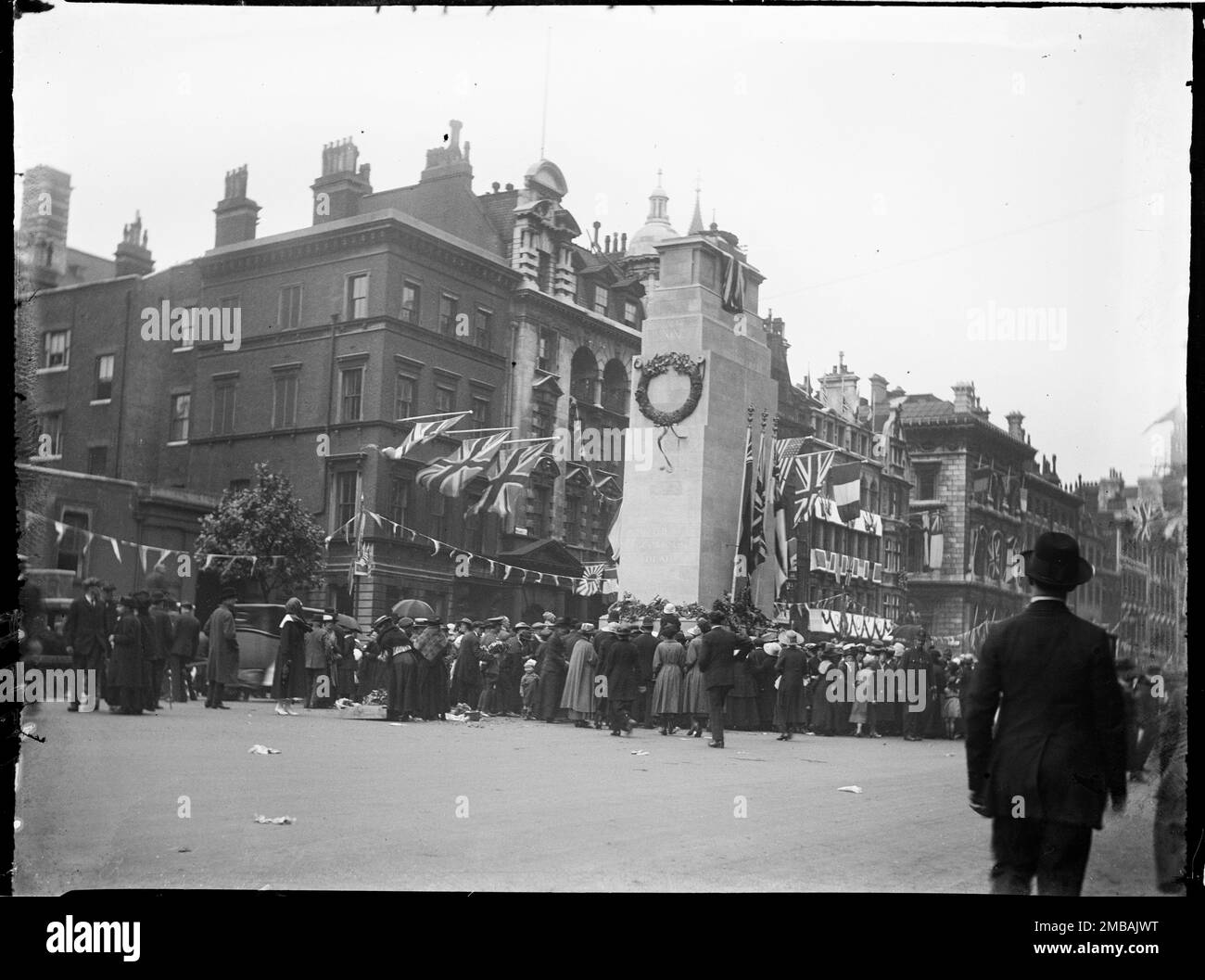 Cenotaph, Whitehall, Westminster, City of Westminster, Greater London Authority, 1919. Ein Blick auf eine Menschenmenge, die sich um den Cenotaph auf Whitehall zu den Feierlichkeiten zum Friedenstag versammelt hat, mit Flaggen und Wölfen auf den Gebäuden dahinter. Dieses Foto gehört zu einer Gruppe, die der Fotograf am 18., 21. &Amp; 23. Juli 1919 aufnahm und die Friedensdekorationen aufnahm, die zum Friedenstag am 19. Juli 1919 in London zur Feier des Endes des 1. Weltkriegs errichtet wurden. Das auf dem Foto gezeigte Zenotaph wurde aus Holz und Putz gebaut und sollte nur eine Woche für den Friedenstag stehen Stockfoto