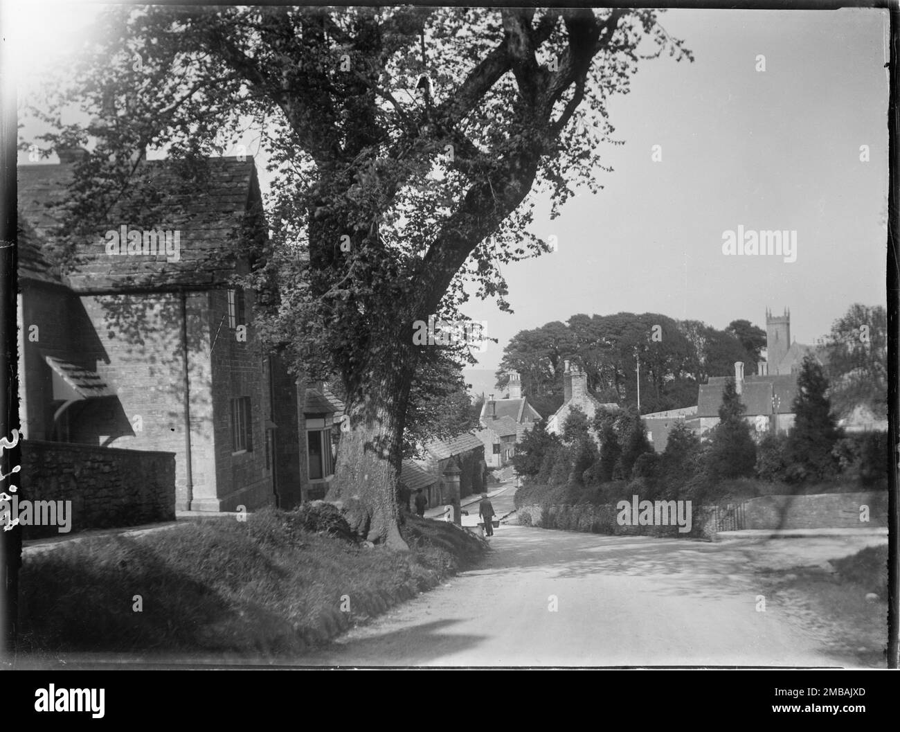 Kingston, Corfe Castle, Purbeck, Dorset, 1927. Von der Kreuzung West Street mit South Street in Kingston aus blickt man nach Osten und zeigt einen Jungen, der zwei Eimer von der Dorfpumpe und dem Turm der Old St James's Church in der Ferne trägt. Stockfoto
