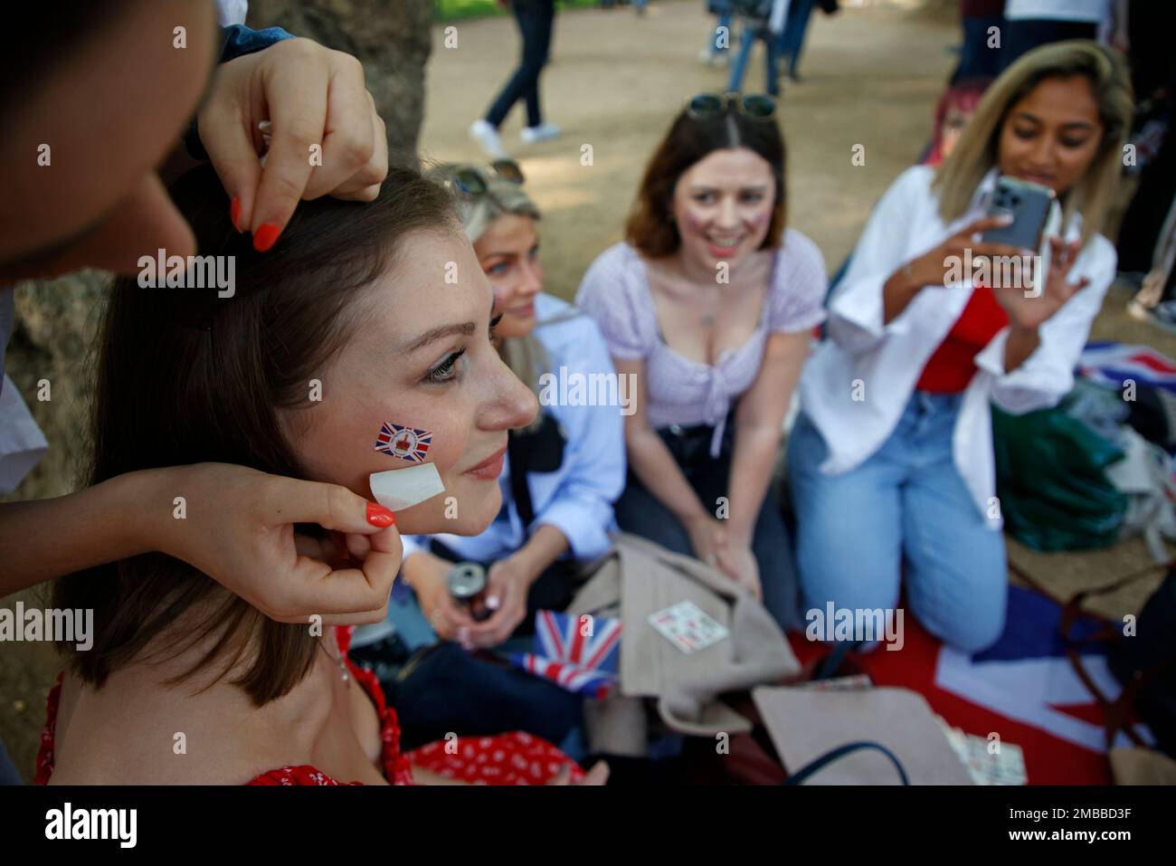Royal fans have Union flag transfers applied to their faces as they gather along the Mall leading to Buckingham Palace in London, Thursday June 2, 2022, on the first of four days of celebrations to mark the Platinum Jubilee. The events over a long holiday weekend in the U.K. are meant to celebrate the monarch's 70 years of service. (AP Photo/David Cliff) Stockfoto
