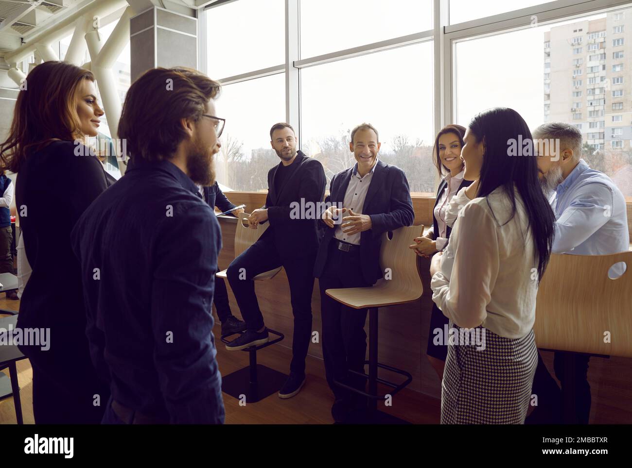 Lächelnde Bürokollegen führen während der Arbeitspause im Büro ein angenehmes Gespräch über ihre Arbeit. Stockfoto