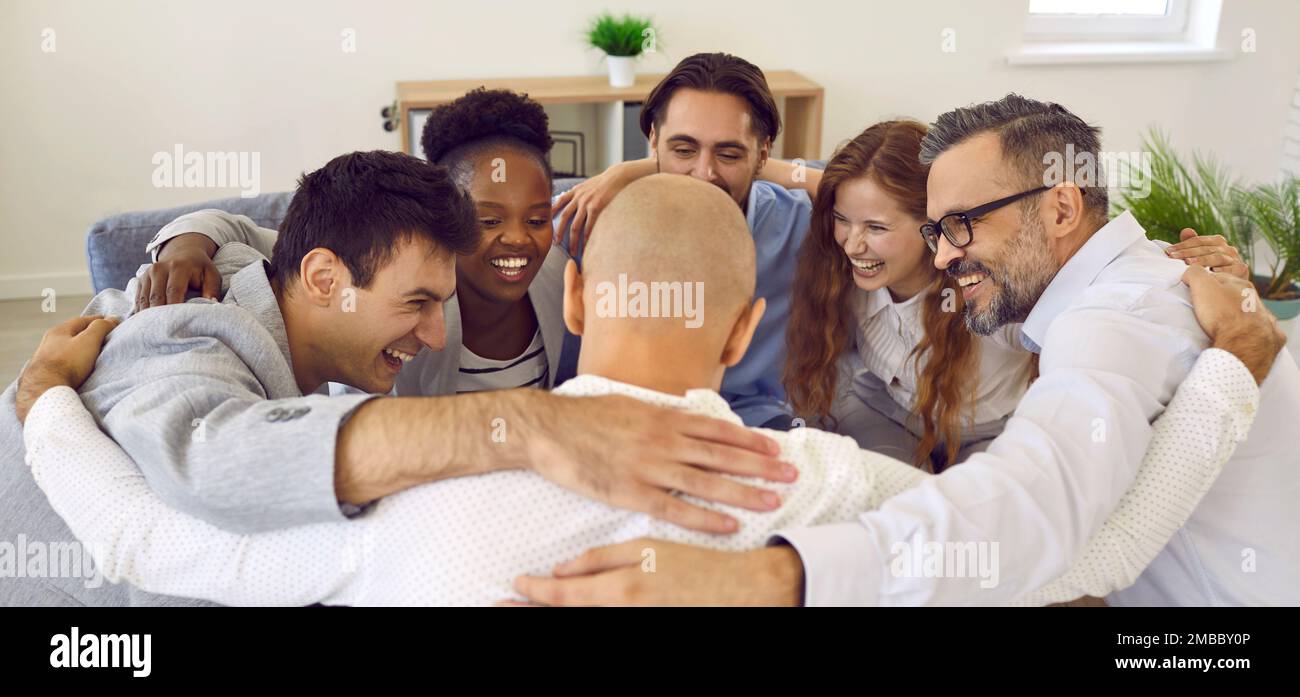 Glückliches Business-Team, das sich im Kreis umarmt, sich freut und ein erfolgreiches Arbeitsergebnis feiert. Stockfoto