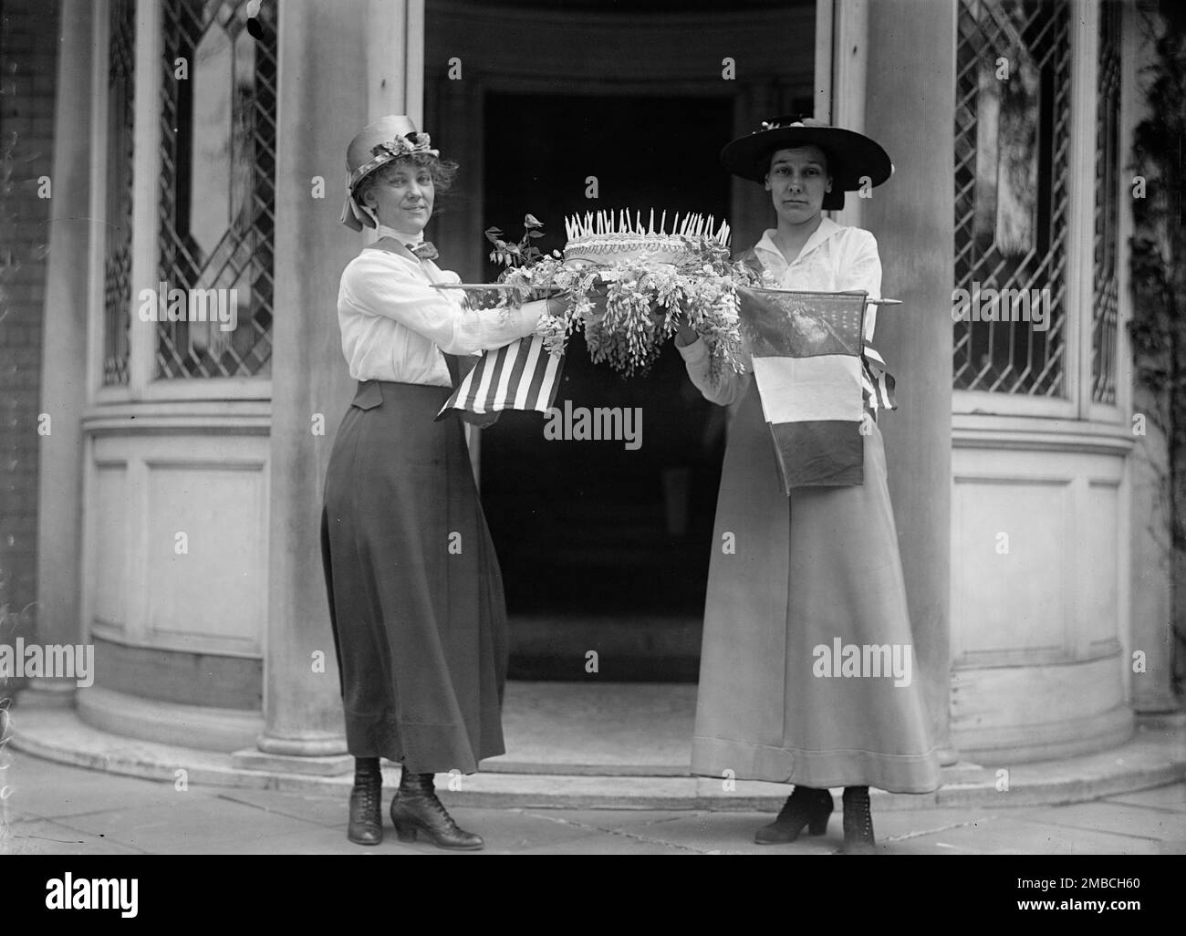 Frauenwahlrecht - Geburtstagskuchen, 1916. Zeigt Gertrude Crocker (rechts, mit breitem Hut), der mit einer anderen Frau, möglicherweise ihrer Schwester Ruth, vor dem Wahlkampf der Congressional Union für Frauen am 21 Madison Place, Washington, D.C. Kuchen hält Crocker war damals stellvertretender Schatzmeister oder Schatzmeister der National Woman's Party. Stockfoto