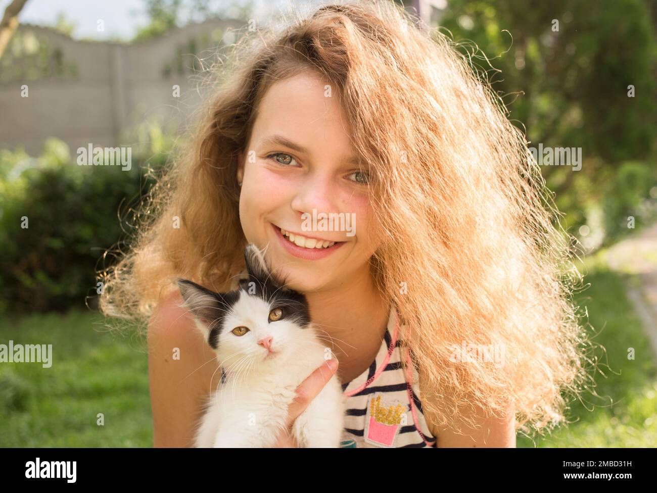 Gesichtsbild eines glücklichen Mädchens, 12 Jahre alt, und eines kleinen schwarz-weißen Kätzchens. Katzentag. Fröhliche Kindheit mit einem flauschigen Lieblingstier. Positive Atmosphäre, Stockfoto