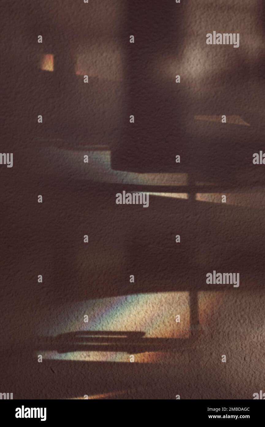 Schatten und Morgenlicht schaffen Visionen moderner Strukturen und Stützen. Die Stuckwand ist in hellen und dunklen Regenbogenfarben gehalten und reflektiert. Stockfoto