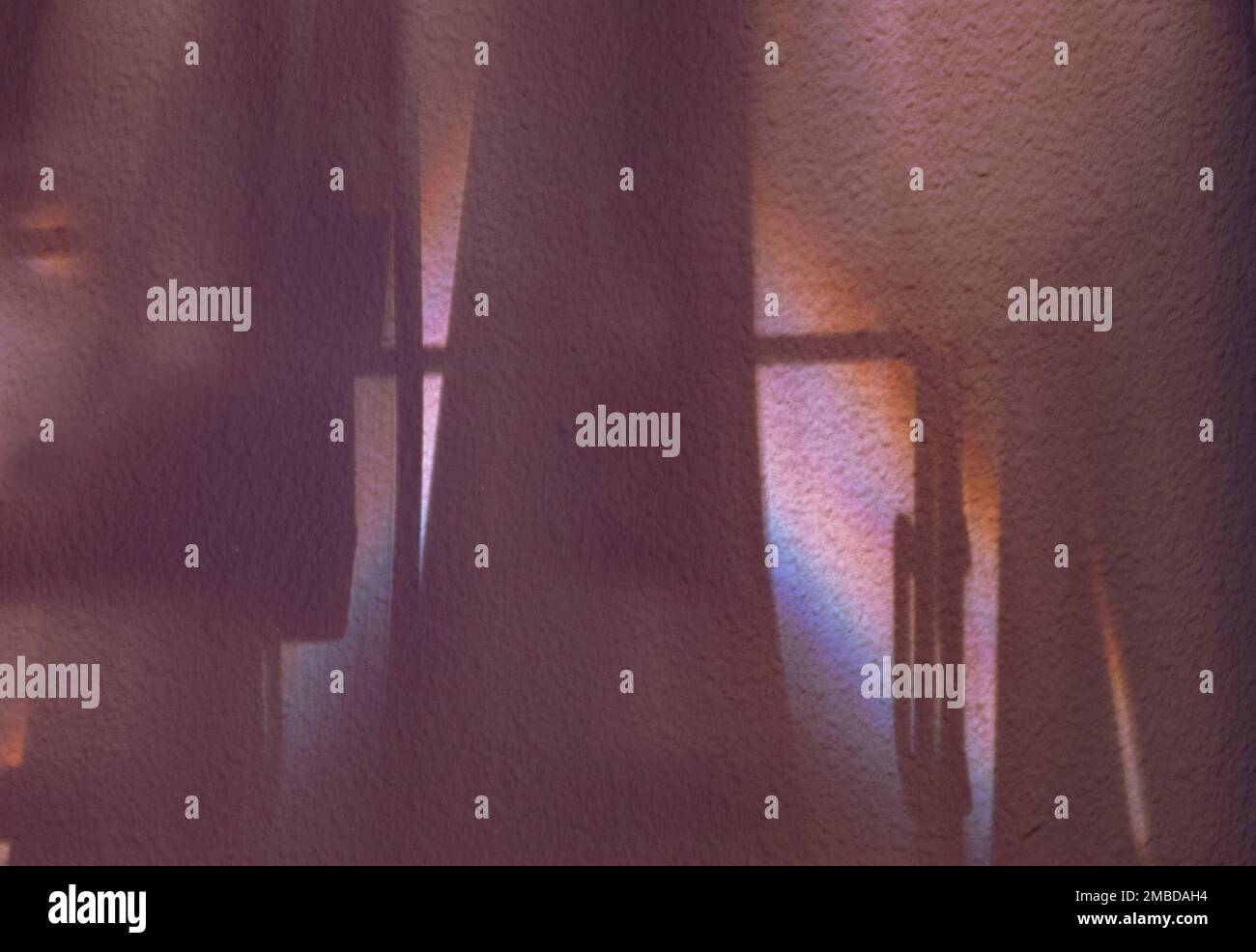 Schatten und Morgenlicht schaffen Visionen moderner Strukturen und Stützen. Die Stuckwand ist in hellen und dunklen Regenbogenfarben gehalten und reflektiert. Stockfoto