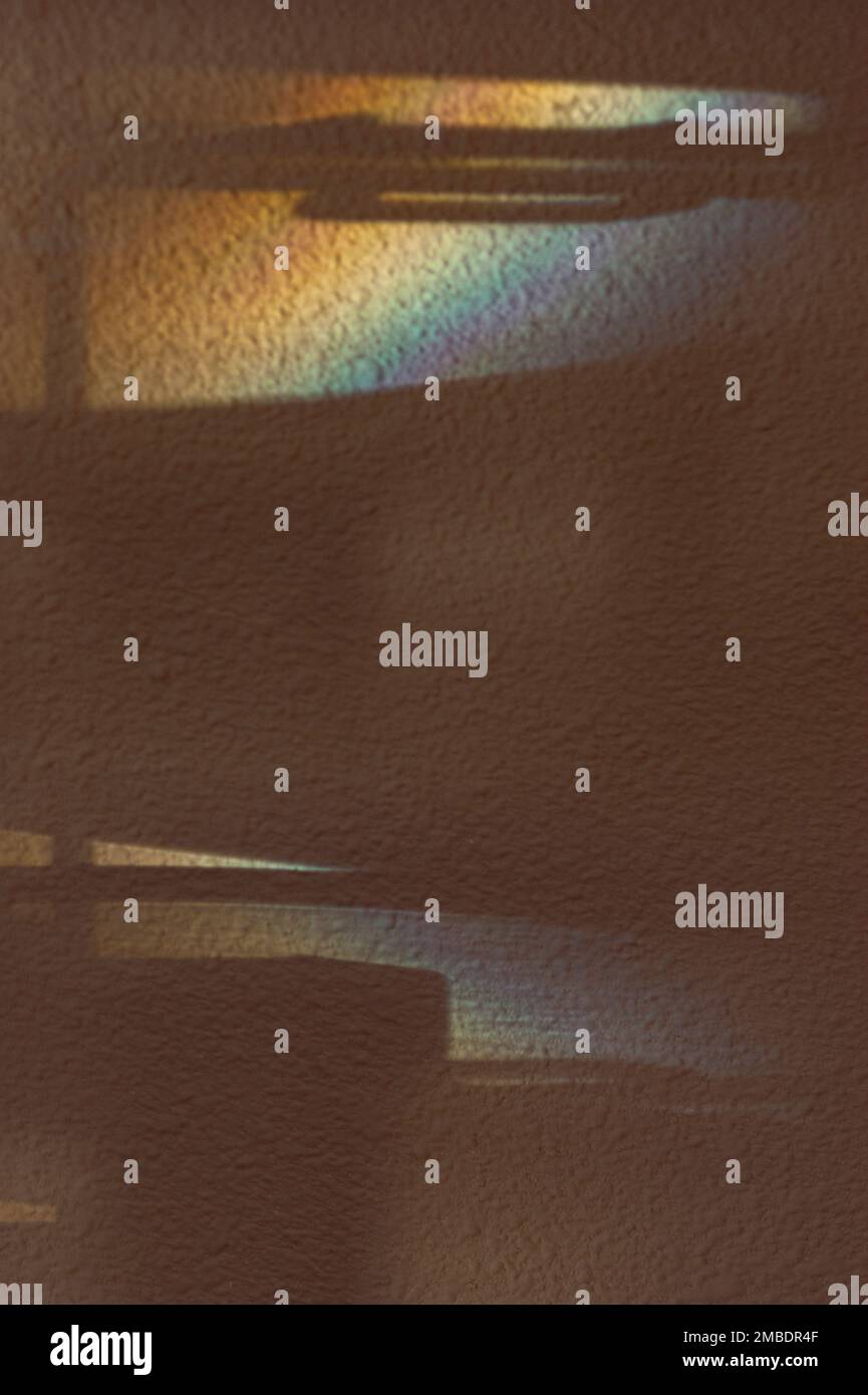 Schatten und Morgenlicht schaffen Visionen moderner Strukturen und Stützen. Die Stuckwand ist in hellen und dunklen Regenbogenfarben gehalten und reflektiert. Stockfoto