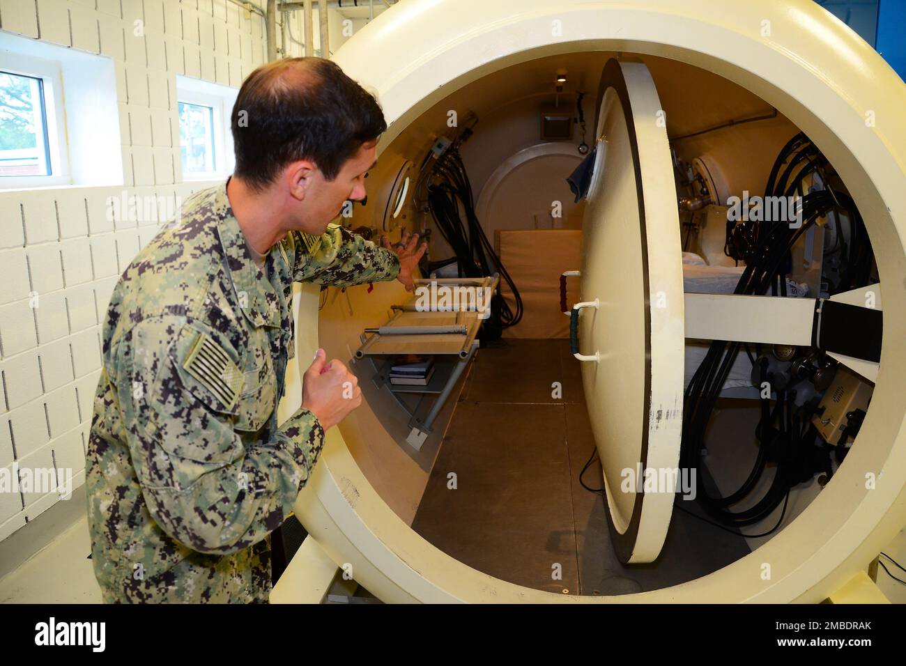 Hospital Corpsman 2. Class Evan Peck, ein Mitglied des Naval Aerospace Medical Institute (NAMI) Hyperbaric Medicine Teams, erklärt, wie die Repressionskammer auf NAS Pensacola funktioniert, 14. Juni 2022. USA Navy-Foto von Joshua Cox Stockfoto