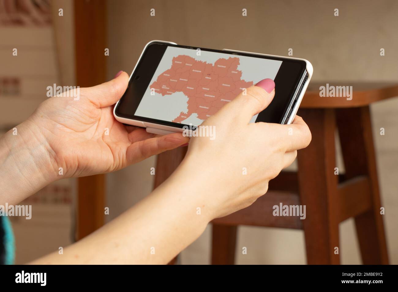 Das Mädchen hält ein Telefon mit einer Karte der Alarmanlagen in der Ukraine, eine Warnung vor Raketen am Himmel über der gesamten Ukraine, einen Krieg in der Ukraine, einen Angriff von Stockfoto