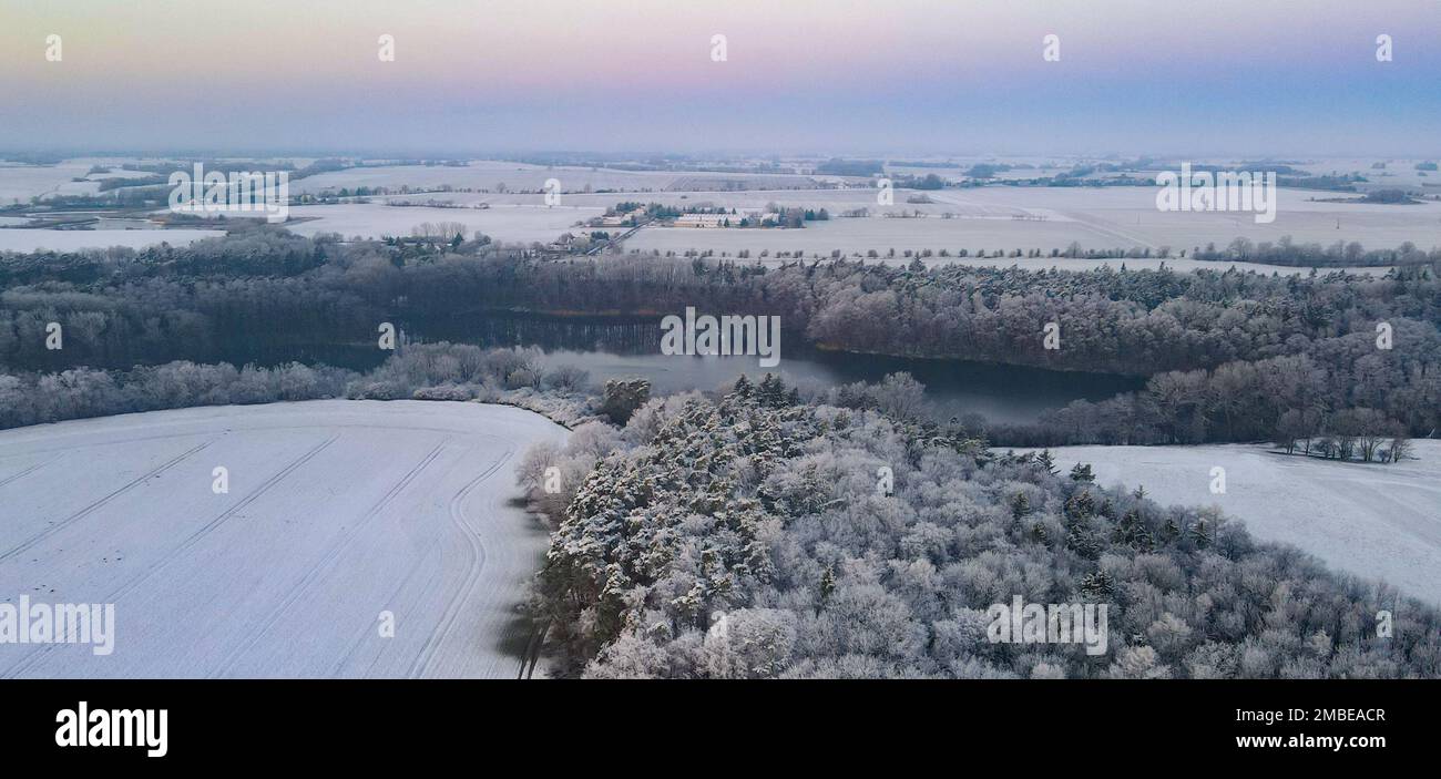 Falkenhagen, Deutschland. 19. Januar 2023. Morgenatmosphäre über der schneebedeckten Winterlandschaft mit Mühlenteich im Bezirk Märkisch-Oderland in Ost-Brandenburg (Luftaufnahme mit einer Drohne). Kredit: Patrick Pleul/dpa/Alamy Live News Stockfoto