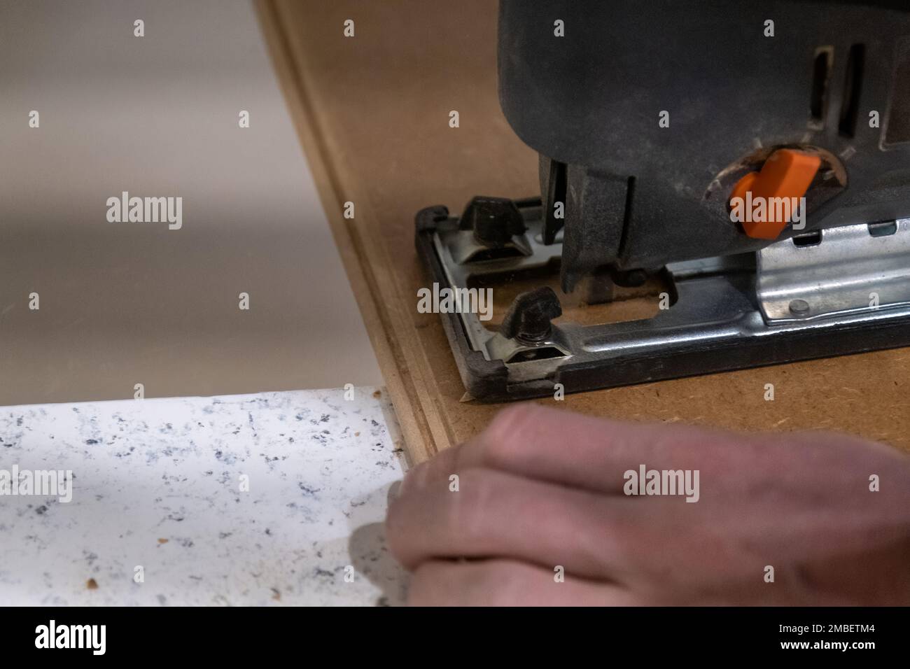 Installation von Laminat in einem Raum schneidet ein Arbeiter eine bestimmte Laminatlänge mit einer Elektrosäge. Selbstreparatur von Fußböden im Haus Stockfoto