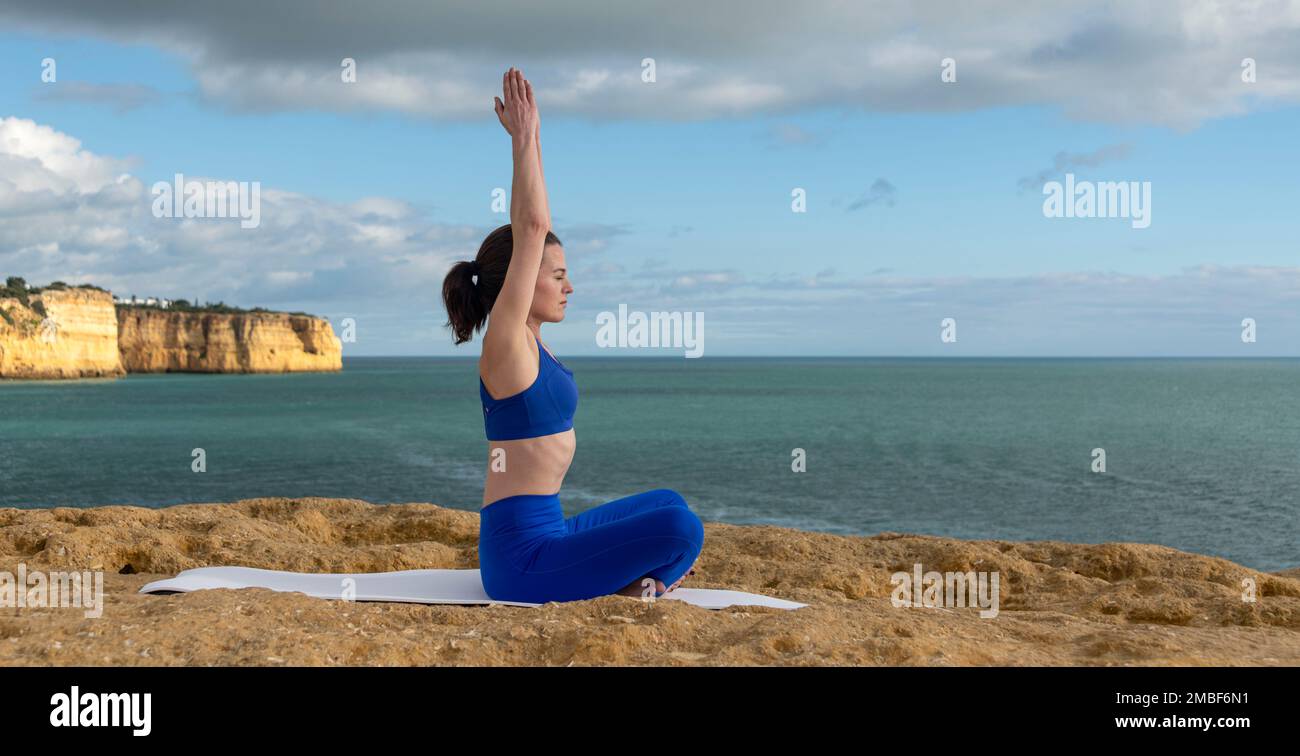 Fit Frau meditiert am Meer, sitzt auf einer Yoga-Matte. Stockfoto