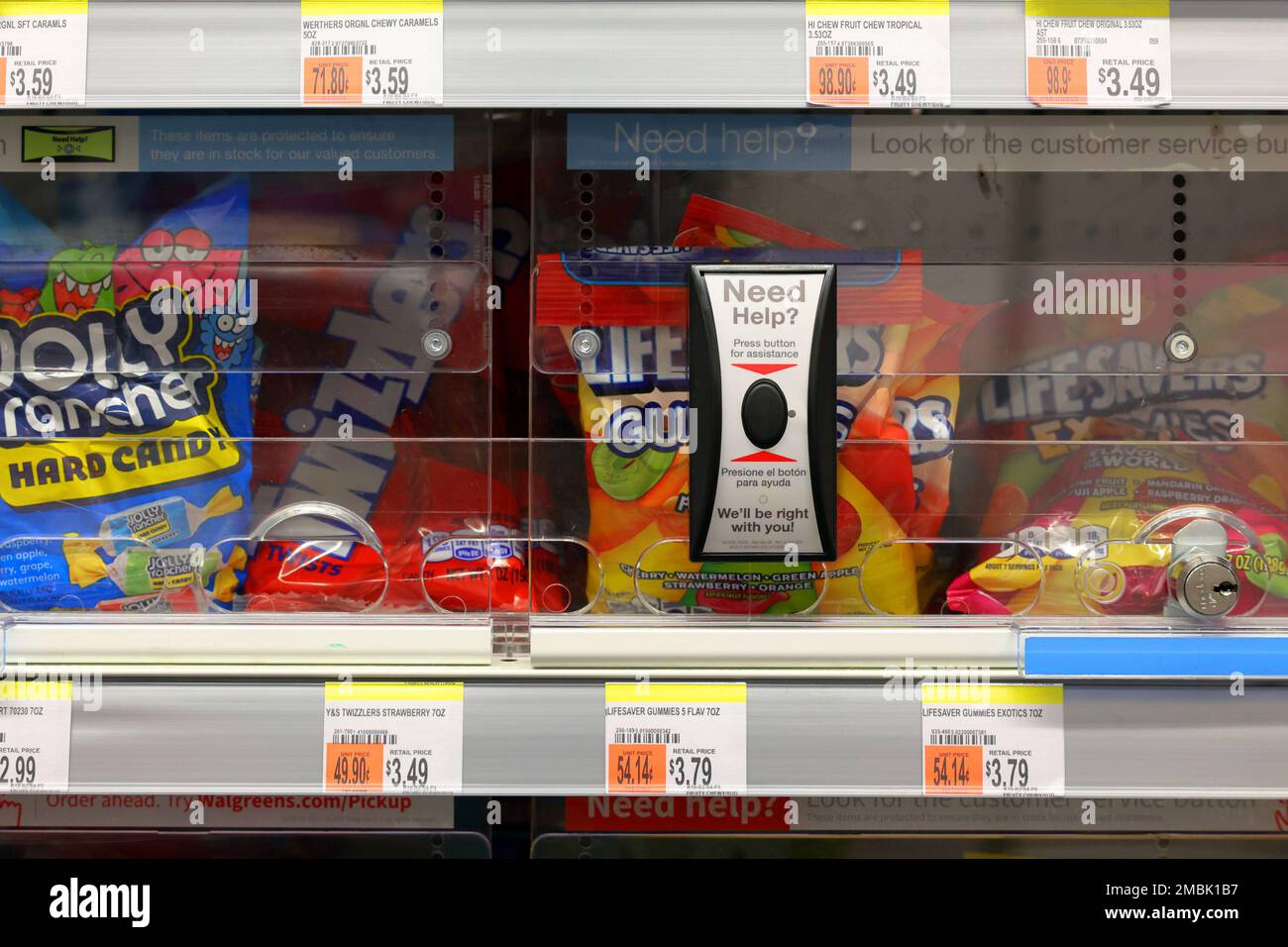 Süßigkeiten auf einem verschlossenen Regal mit einer drahtlosen Kundenservice-Anruftaste, die Hilfe beim Entsperren der besagten Artikel in einer Walgreens-Drogerie anfordert. Stockfoto