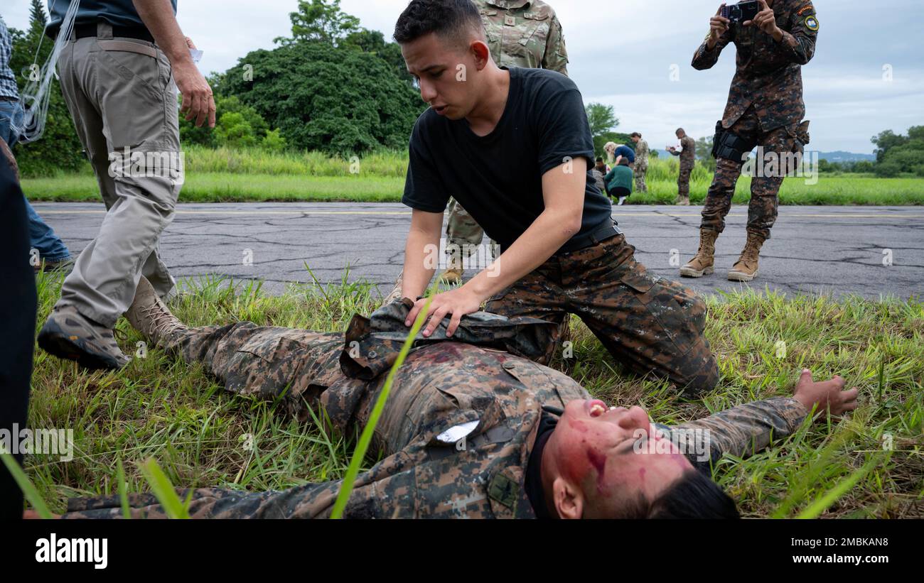 Ein Sanitäter aus El Salvador (oben Mitte) überprüft einen simulierten Überlebenden eines Flugzeugabsturzes (unten Mitte) auf unmittelbare Verletzungen am Luftwaffenstützpunkt Ilopango, El Salvador, 16. Juni 2022. Resolute Sentinel 22 ist eine Übung, die militärische medizinische Fachkräfte auf den Einsatz und die Durchführung gemeinsamer Operationen unter strengen Bedingungen vorbereiten soll. Stockfoto