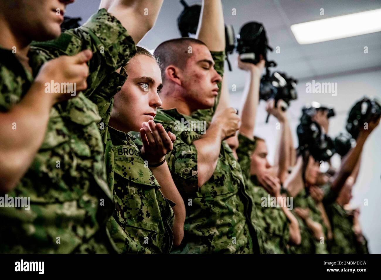 220617-N-PW480-0054 GREAT LAKES, ILLINOIS (17. Juni 2022) – Naval Reserve Officers Training Corps (NROTC) New Student Indoctrination (NSI) Midshipman Kandidaten halten ihre Gasmasken hoch, bevor sie die Vertrauenskammer beim Recruit Training Command (RTC) betreten, Juni 17. Nach Abschluss des NSI beginnen die Kandidaten in diesem Herbst ihr erstes Jahr des NROTC-Programms an Hochschulen und Universitäten im ganzen Land. NSI ist ein Indoktrinierungsprogramm, das bei RTC ausgerichtet wird und den Fähnrich-Fähnrich eine gemeinsame militärische Ausbildung vermittelt. NSI bietet Grundausbildung in fünf Grundlagen der Kriegsführung an – Feuergefecht Stockfoto