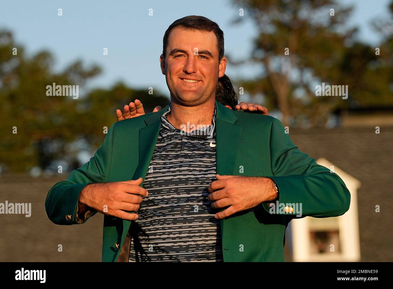 Hideki Matsuyama, of Japan, helps Scottie Scheffler put on the green jacket after winning the 86th Masters golf tournament on Sunday, April 10, 2022, in Augusta, Ga. (AP Photo/David J. Phillip) Stockfoto