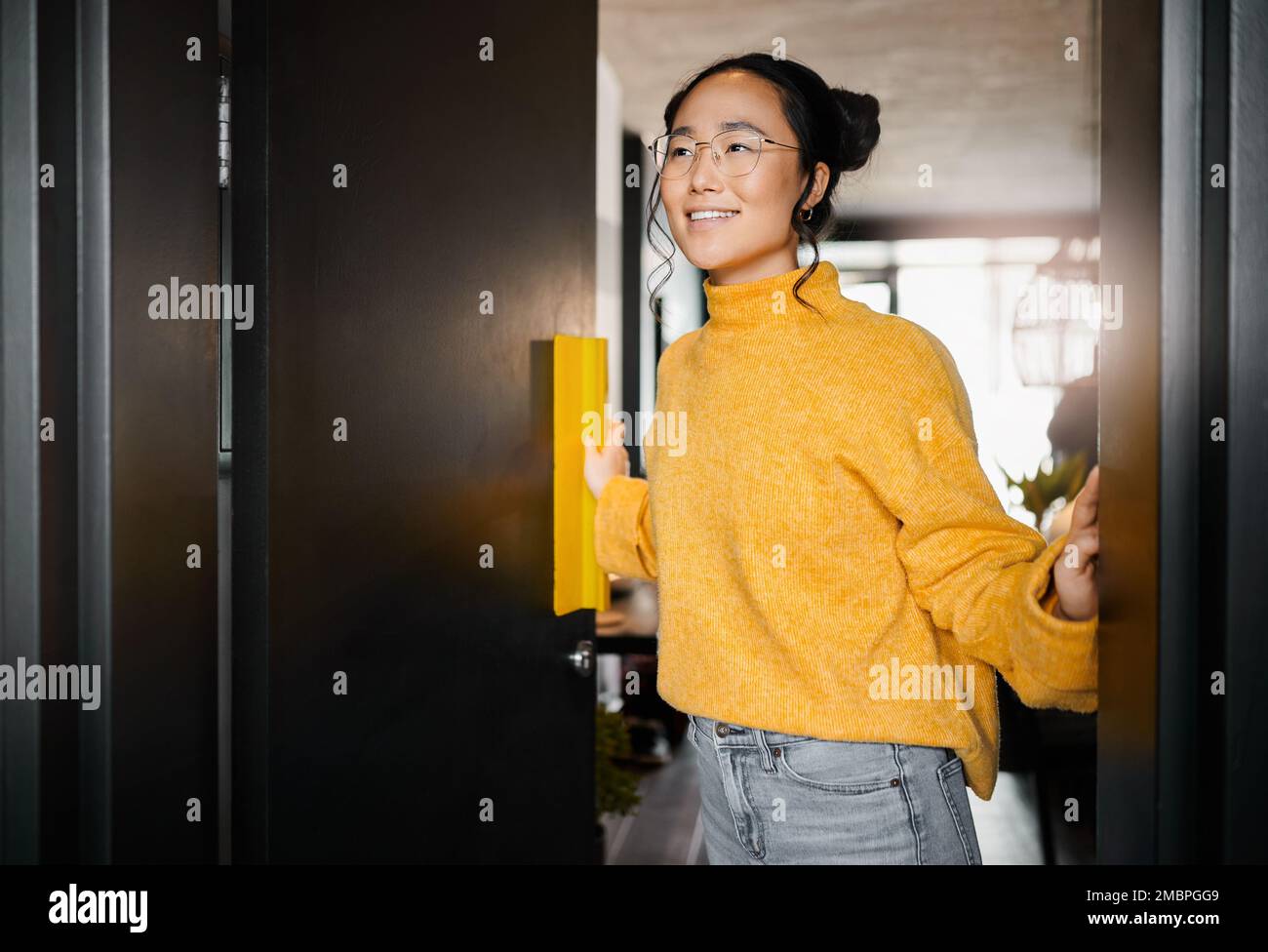 Denken, Lächeln und eine Asiatin, die eine Tür zu einem Büro in einem Startup-Unternehmen für Grafikdesign öffnet. Vision, glücklicher und japanischer Designer am Eingang Stockfoto