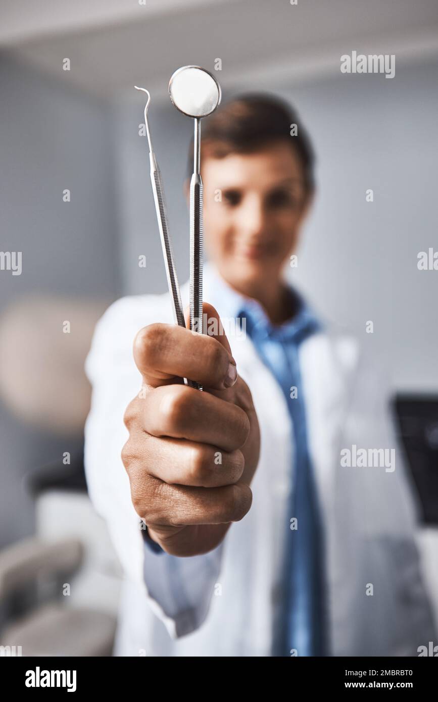 Ein Superzahnarzt benutzt Superwerkzeuge. Porträt einer jungen Frau mit zahnärztlichen Werkzeugen in ihrer Praxis. Stockfoto