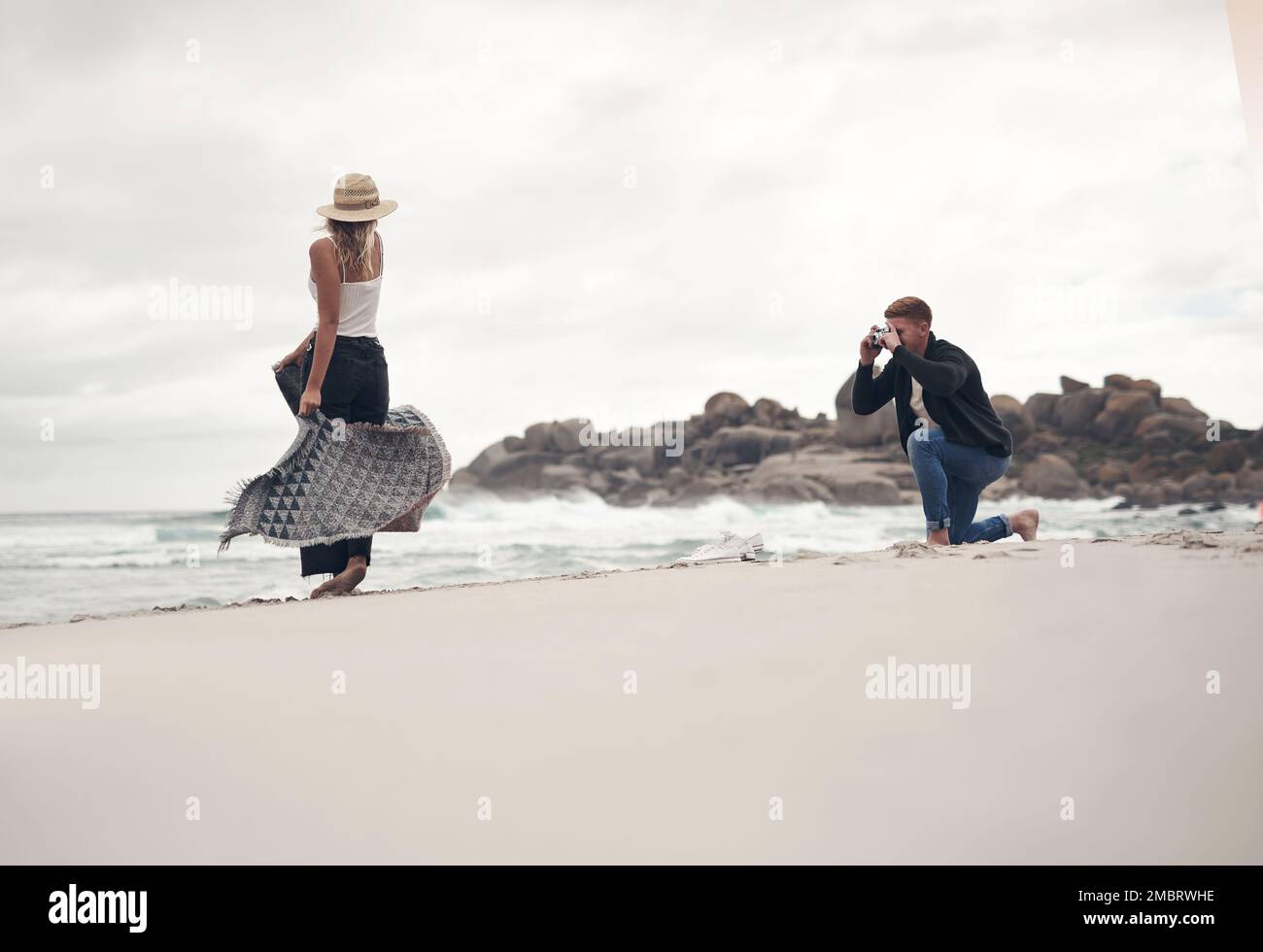 Ich liebe es, wenn sie für mich modelt. Ein Mann, der Fotos von seiner Freundin macht, während er Zeit am Strand verbringt. Stockfoto