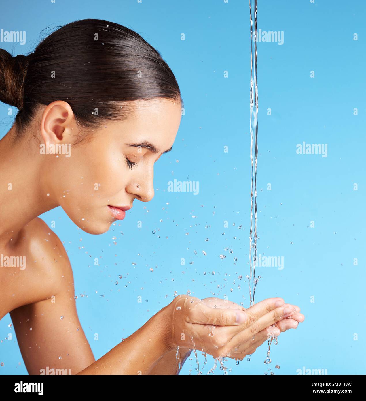 Frau, Hände und Wasser für Gesichtswäsche, Hautpflege, Hydratation oder Hygiene vor blauem Hintergrund. Schönes weibliches Modell in der Gesichtsreinigung, -Reinigung oder Stockfoto
