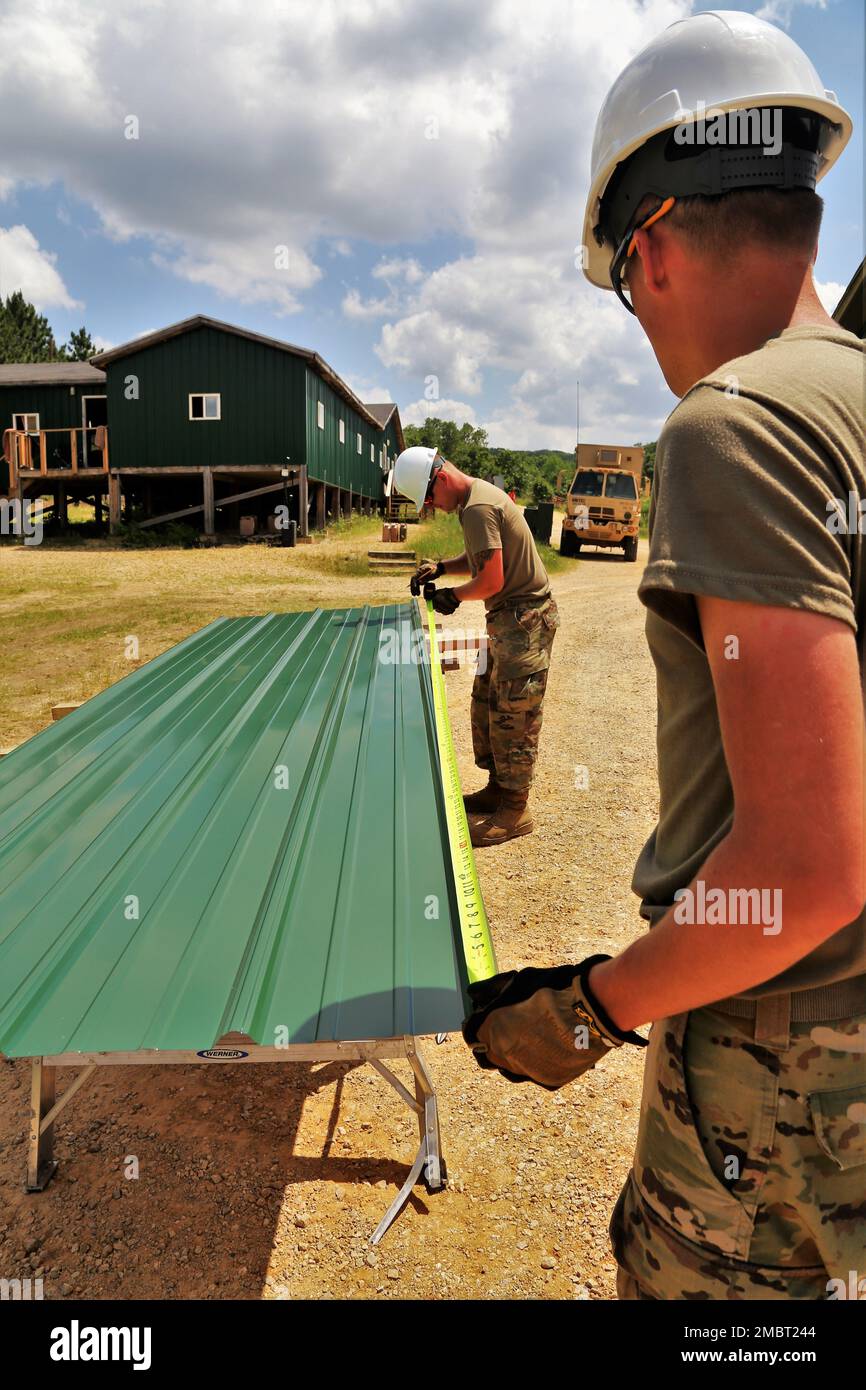 Soldaten der 389. Engineer Company des Army Reserve in des Moines, Iowa, arbeiten am 21. Juni 2022 an einem Truppenprojekt im Camp Courage auf der South Post in Fort McCoy, Wisconsin. Das Unternehmen arbeitete im Rahmen seiner jährlichen Schulung 2022 an mehreren Projekten zur Verbesserung des Lagers, einschließlich der Montage neuer Metallverkleidungen an zahlreichen Gebäuden. Die Truppenprojekte werden von der Direktion für öffentliche Arbeiten von Fort McCoy koordiniert und tragen zur Verbesserung der Infrastruktur der Anlage bei, während gleichzeitig die Ausbildung von Armeeingenieureinheiten stattfindet. Stockfoto