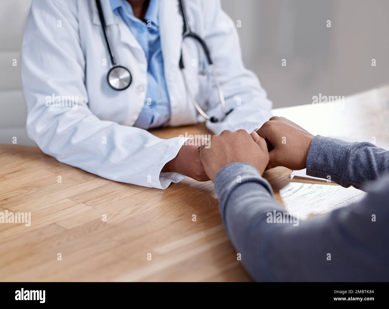Gute medizinische Fachkräfte zeigen Mitgefühl und bieten den Patienten Komfort. Nahaufnahme eines unbekannten Arztes, der mit einem Patienten Hand hält Stockfoto