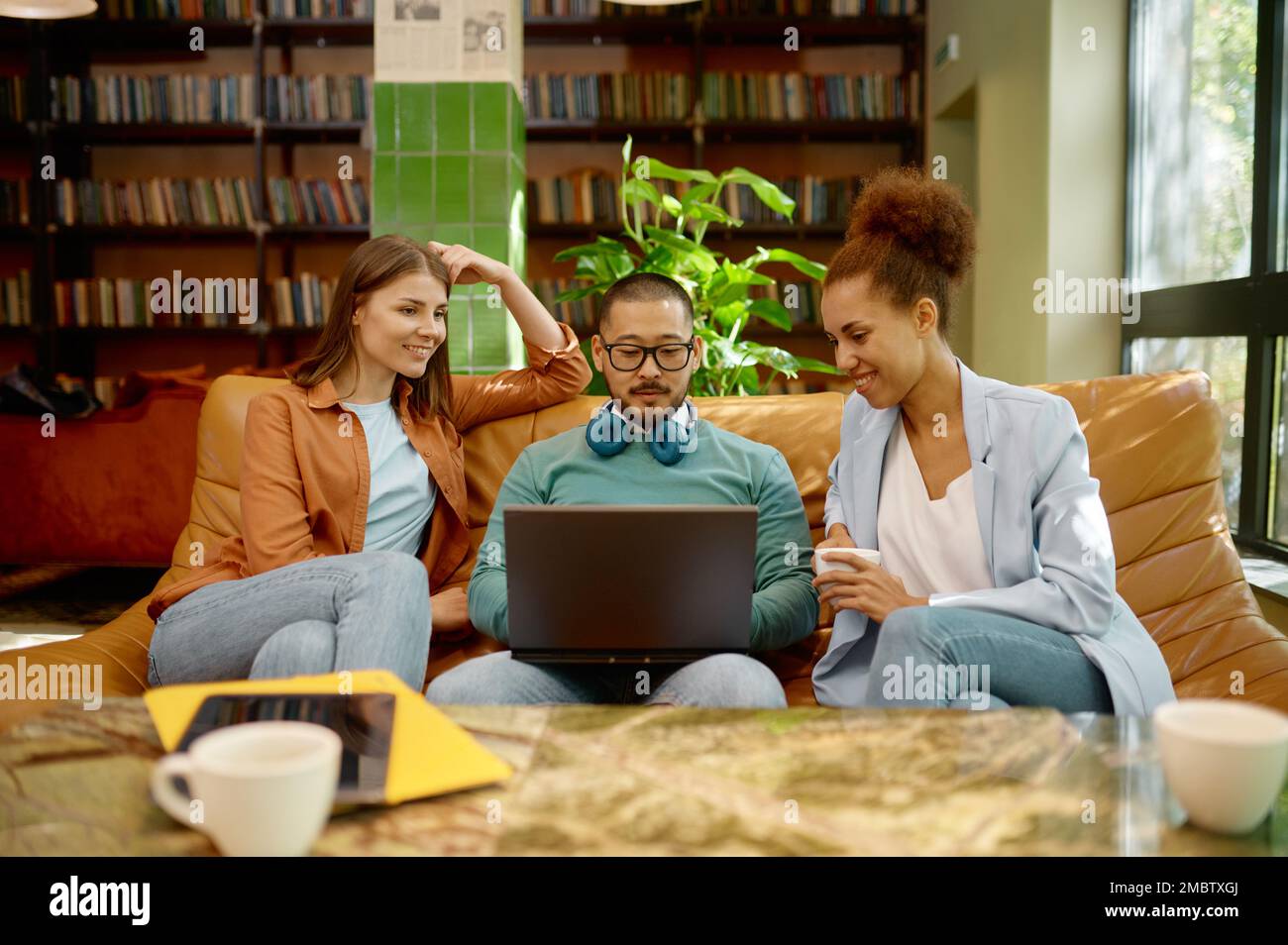 Mitarbeiter zeigt Teamkollegen Geschäftslösungen auf dem Laptop-Bildschirm im Gemeinschaftsarbeitsbereich Stockfoto