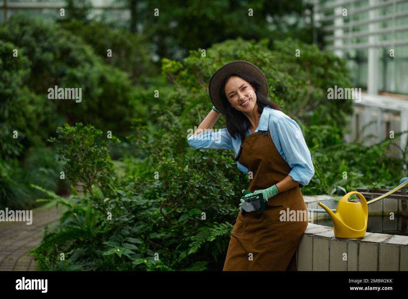 Junge Gärtnerin, stolz auf die Schönheit ihres eigenen Gewächshauses Stockfoto