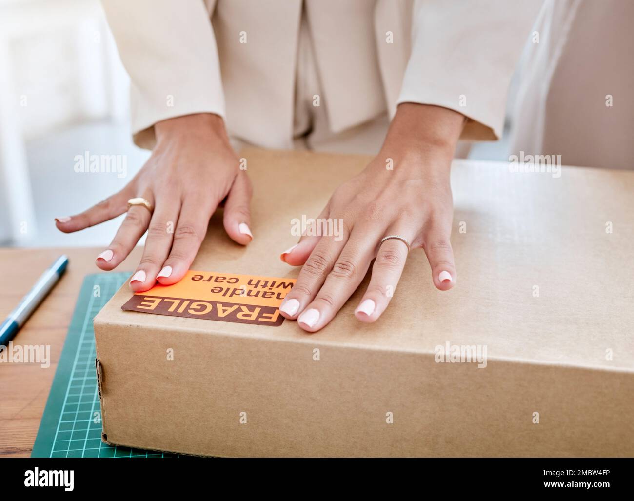 Hände, Logistik und zerbrechlicher Karton für Versand, Lieferung oder Verpackung in E-Commerce, Fracht oder Bestand in der Werkstatt. Hand des Geschäftseigentümers, der den Artikel verpackt Stockfoto