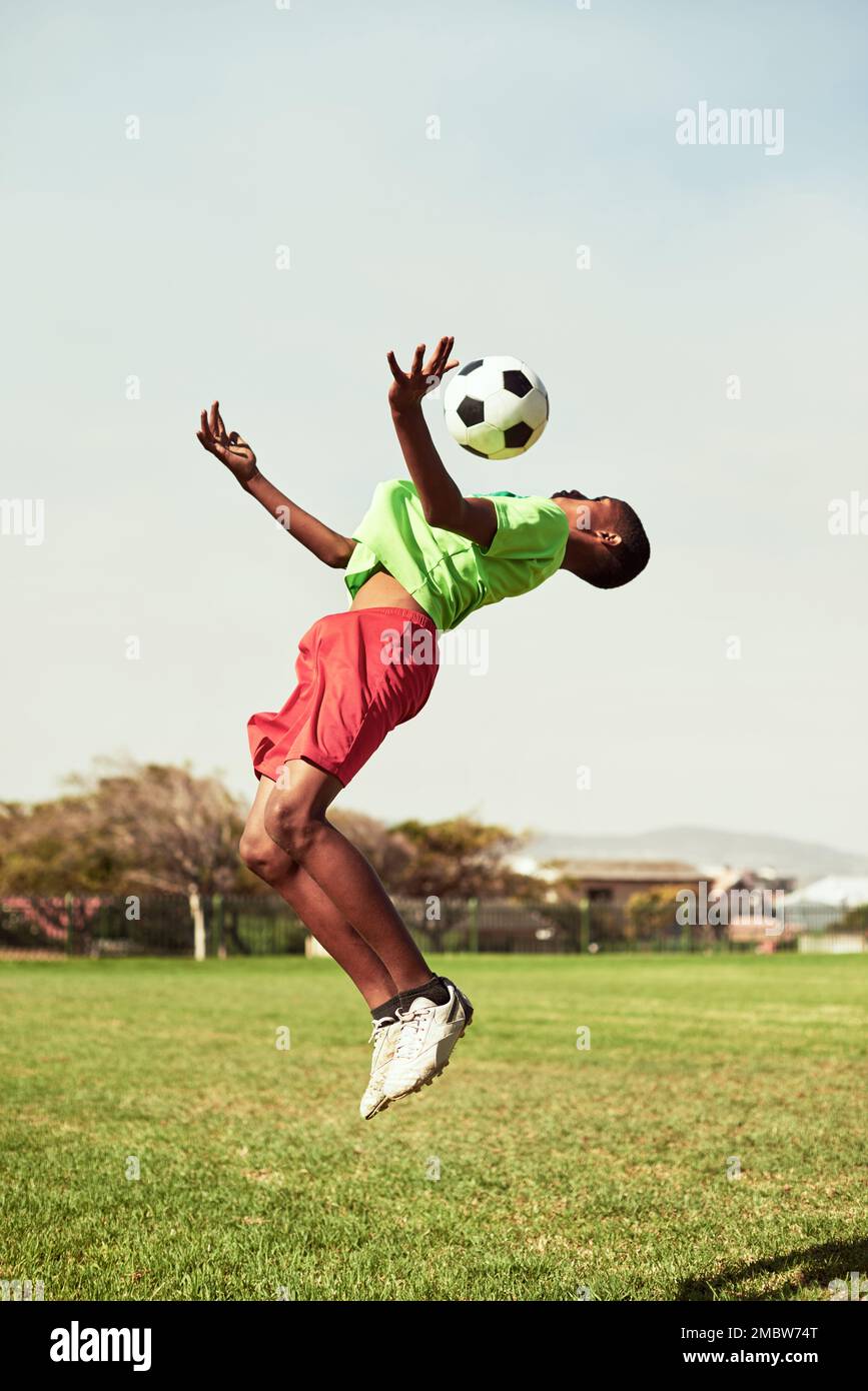 Sie zeigen großes Können und Agilität. Ein kleiner Junge, der Fußball auf einem Sportplatz spielt. Stockfoto