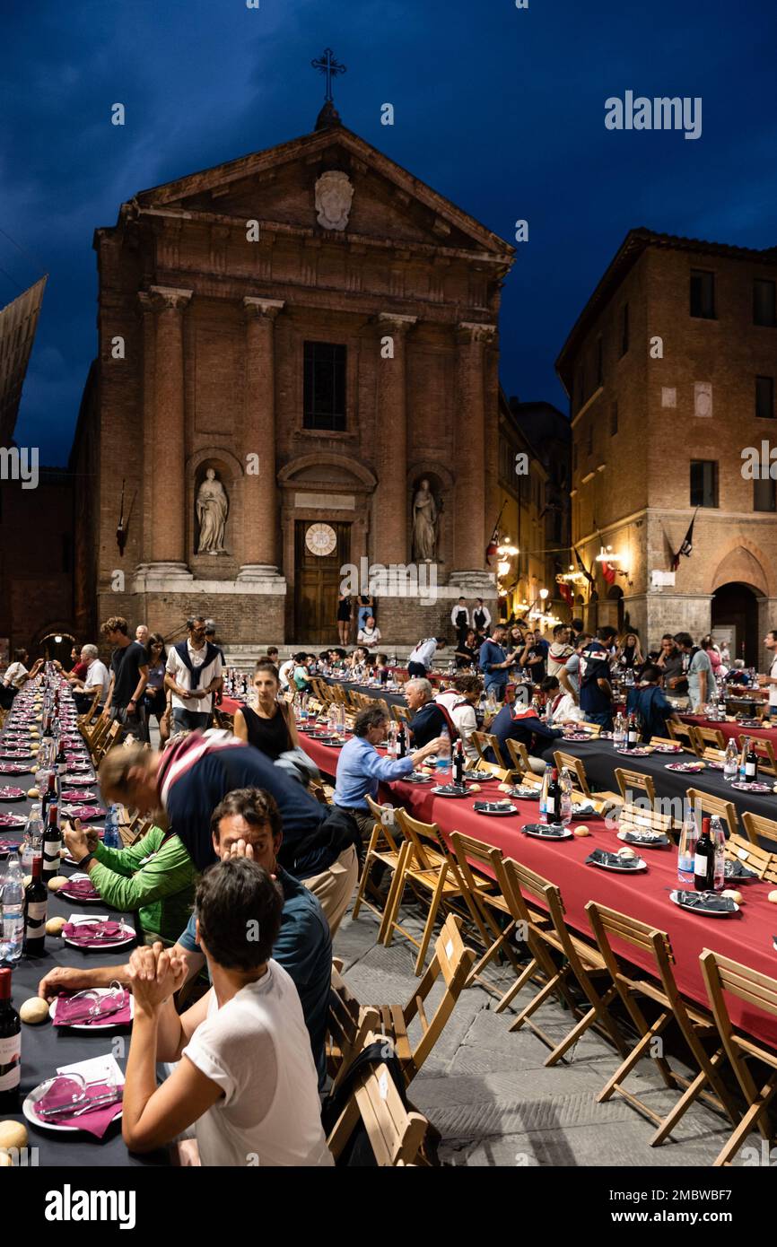 Siena, Italien - August 15 2022: Das große Contrada-Dinner der Civetta oder der kleinen Eule Contrada am Abend vor dem Palio dell Assunta auf der Piazza to Stockfoto