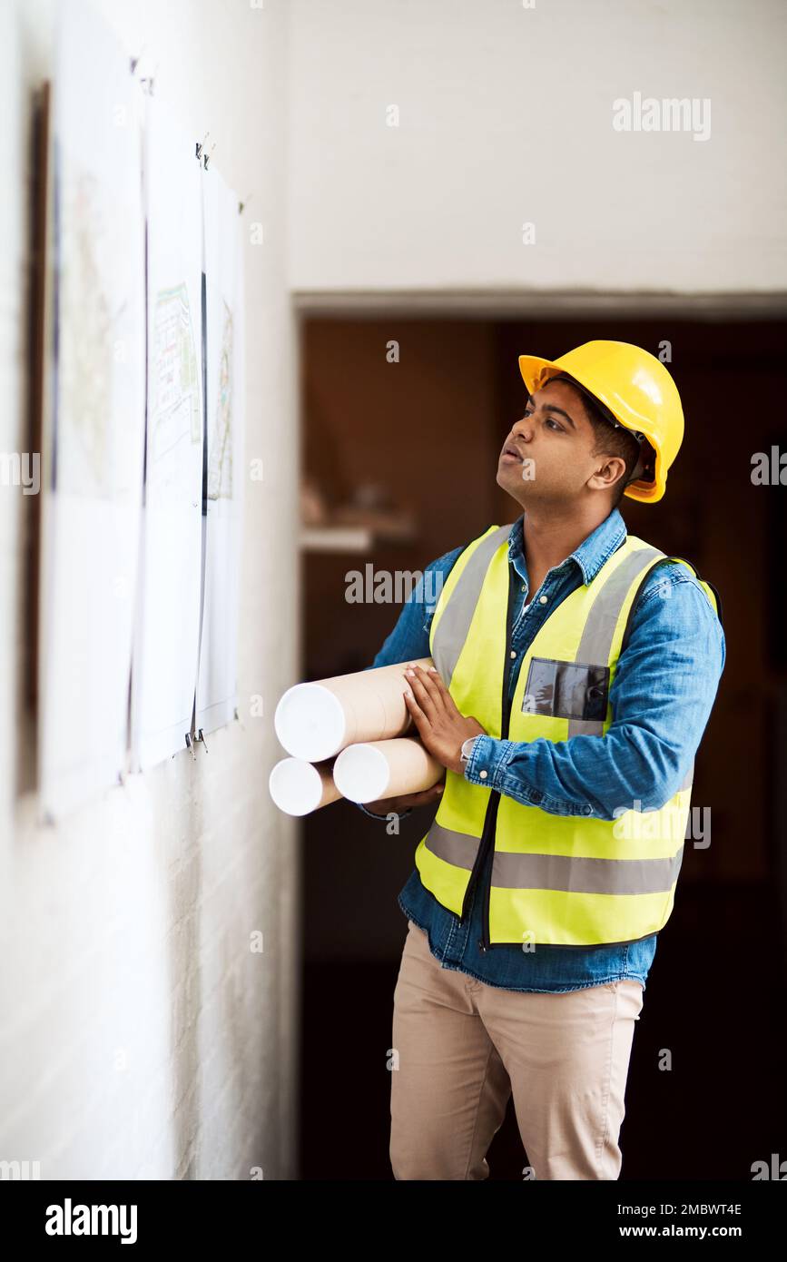 Bereit, Ideen in die Tat umzusetzen. Ein junger Ingenieur, der etwas an der Wand liest. Stockfoto