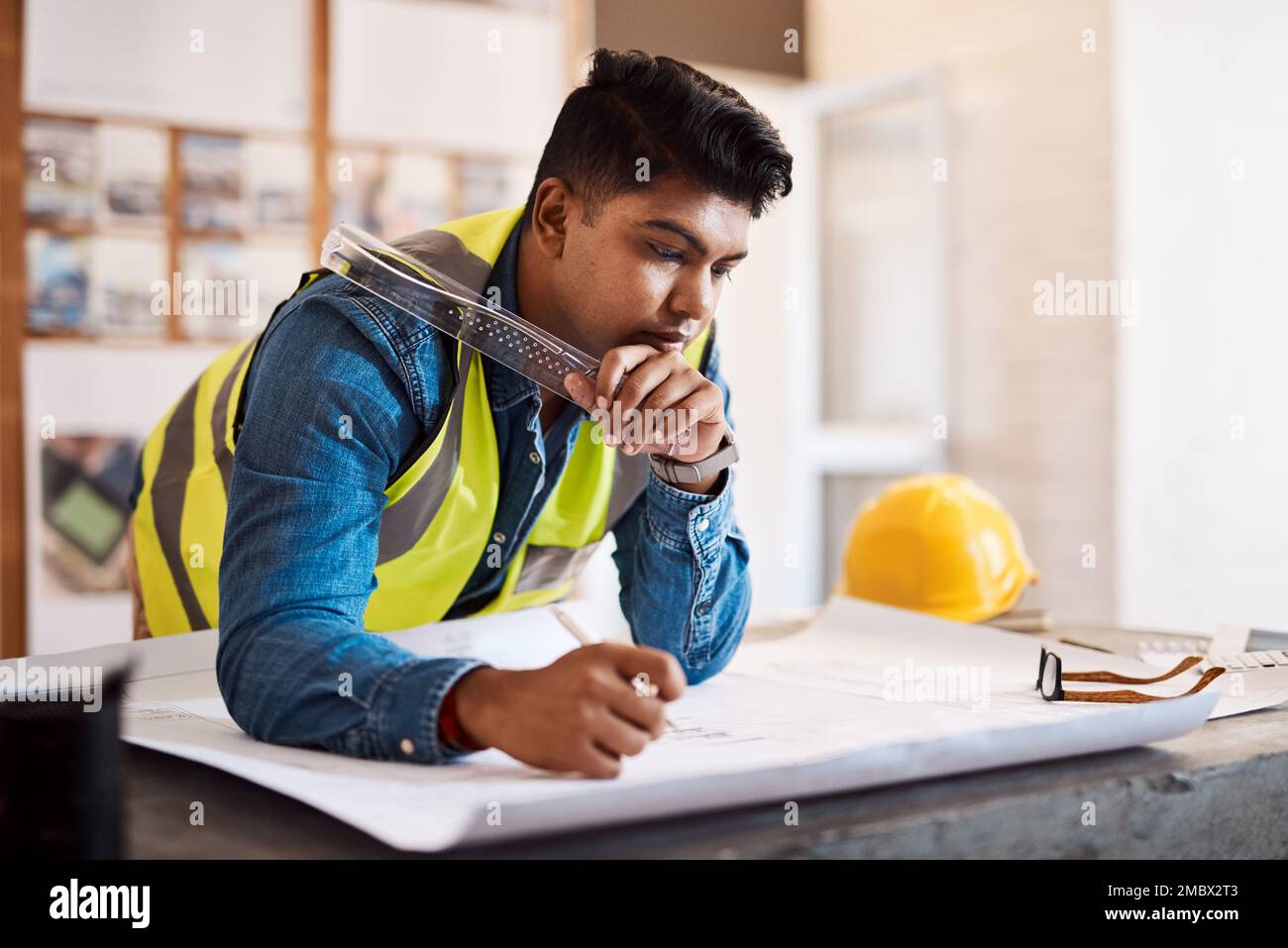 Es gibt keinen Raum für Fehler, wenn es um Baupläne geht. Ein junger Architekt, der in seinem Büro einen Bauplan aufstellt. Stockfoto