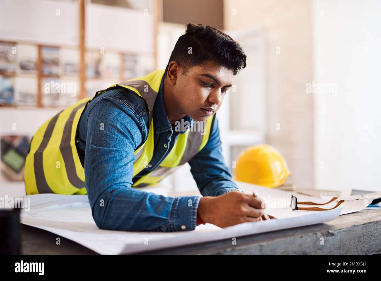Seine Entwürfe enttäuschen nie. Ein junger Architekt, der in seinem Büro einen Bauplan aufstellt. Stockfoto