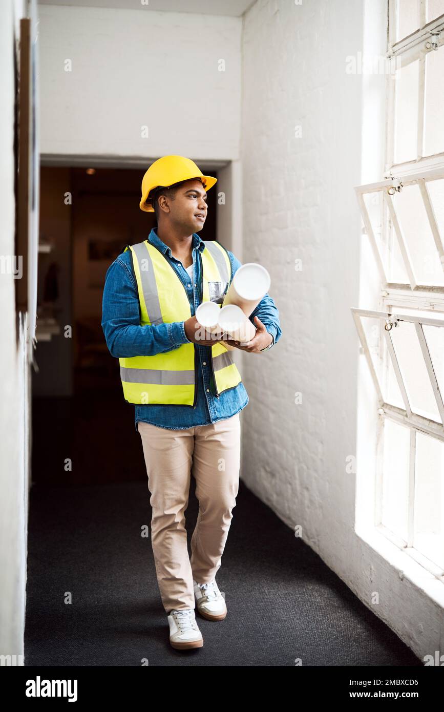 Ich habe tolle Pläne für dieses Gebäude. Ein junger Ingenieur, der Baupläne auf einer Baustelle hält. Stockfoto