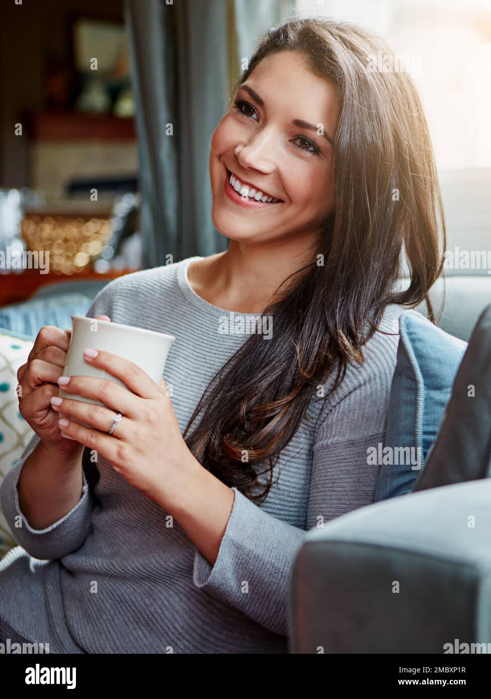 Entspannen Sie sich, Kaffee und Frau auf dem Sofa, denken und junge Frau im Wohnzimmer, Ruhe und Wochenendausflug. Lady, Mädchen auf der Couch und Tee für Frieden und Glück Stockfoto