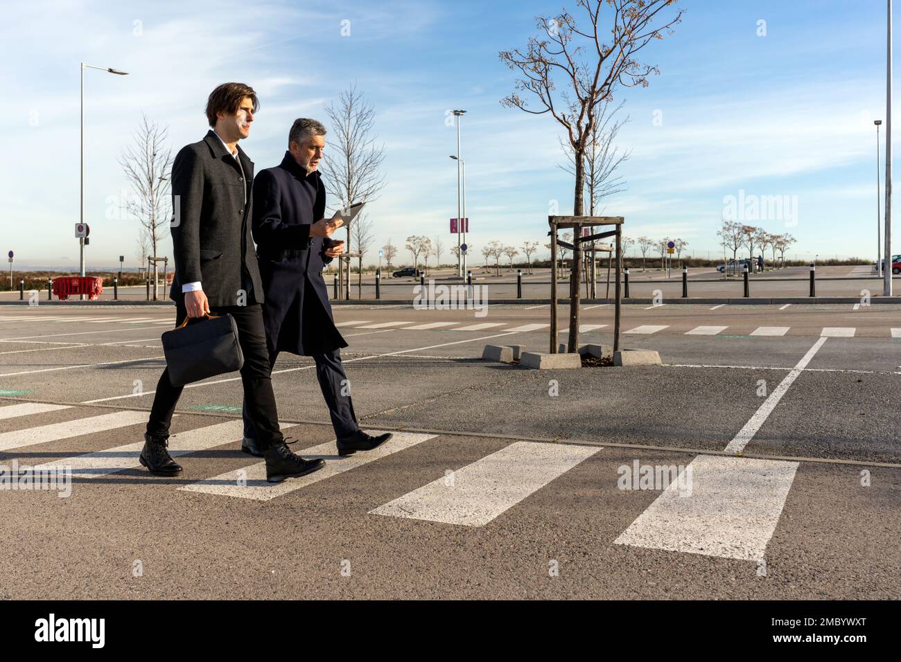 Ein ganzer Körper selbstbewusster Geschäftsleute in formeller Kleidung, die während des Meetings auf einem Gehweg unterwegs sind Stockfoto