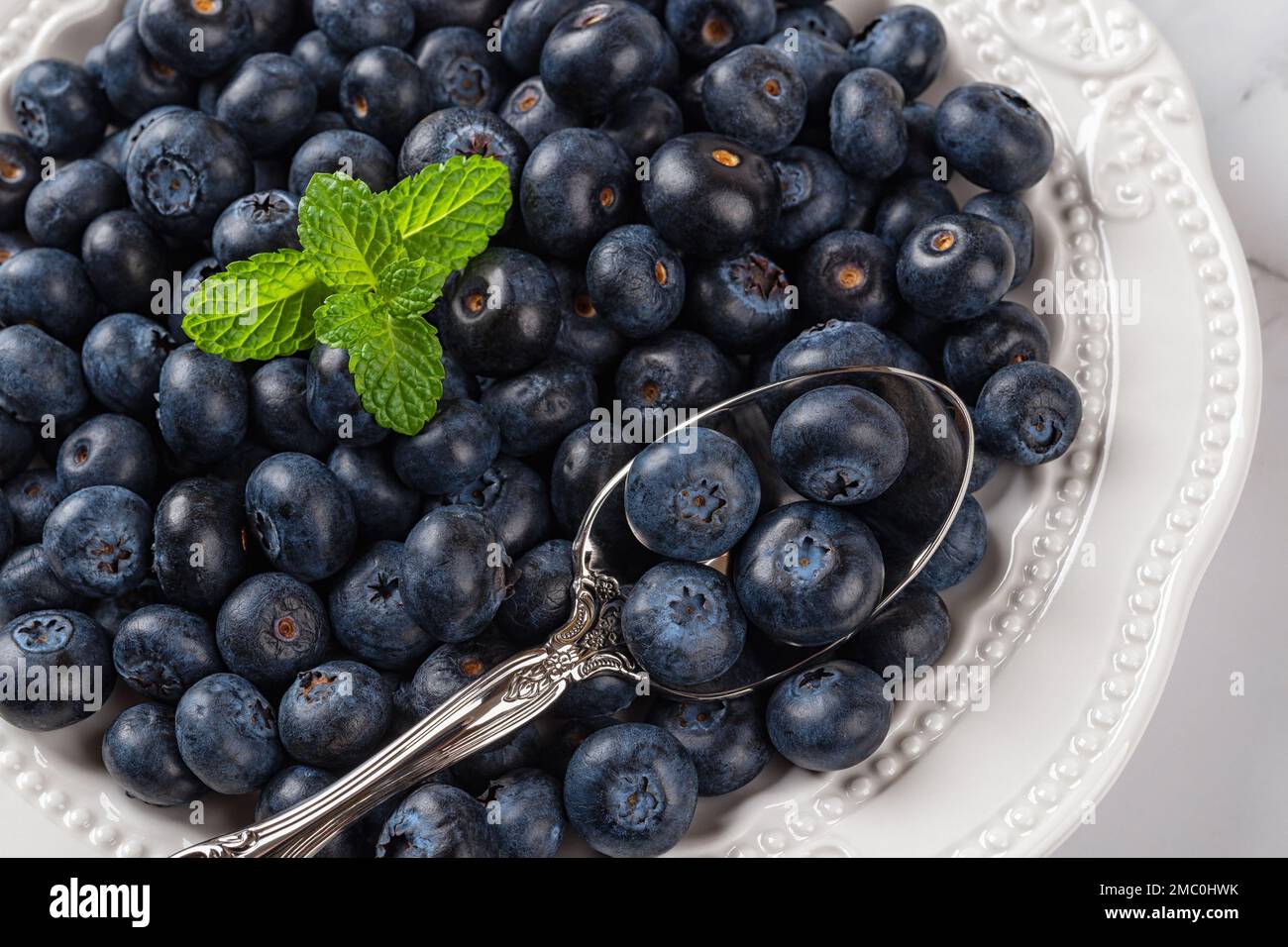 Teller voll mit süßen Blaubeeren. Reife, saftige Blaubeeren als Entgiftungsfuttermittel. Vegetarisches Bio-Dessert. Veganer Vitamin-Snack. Makro. Stockfoto